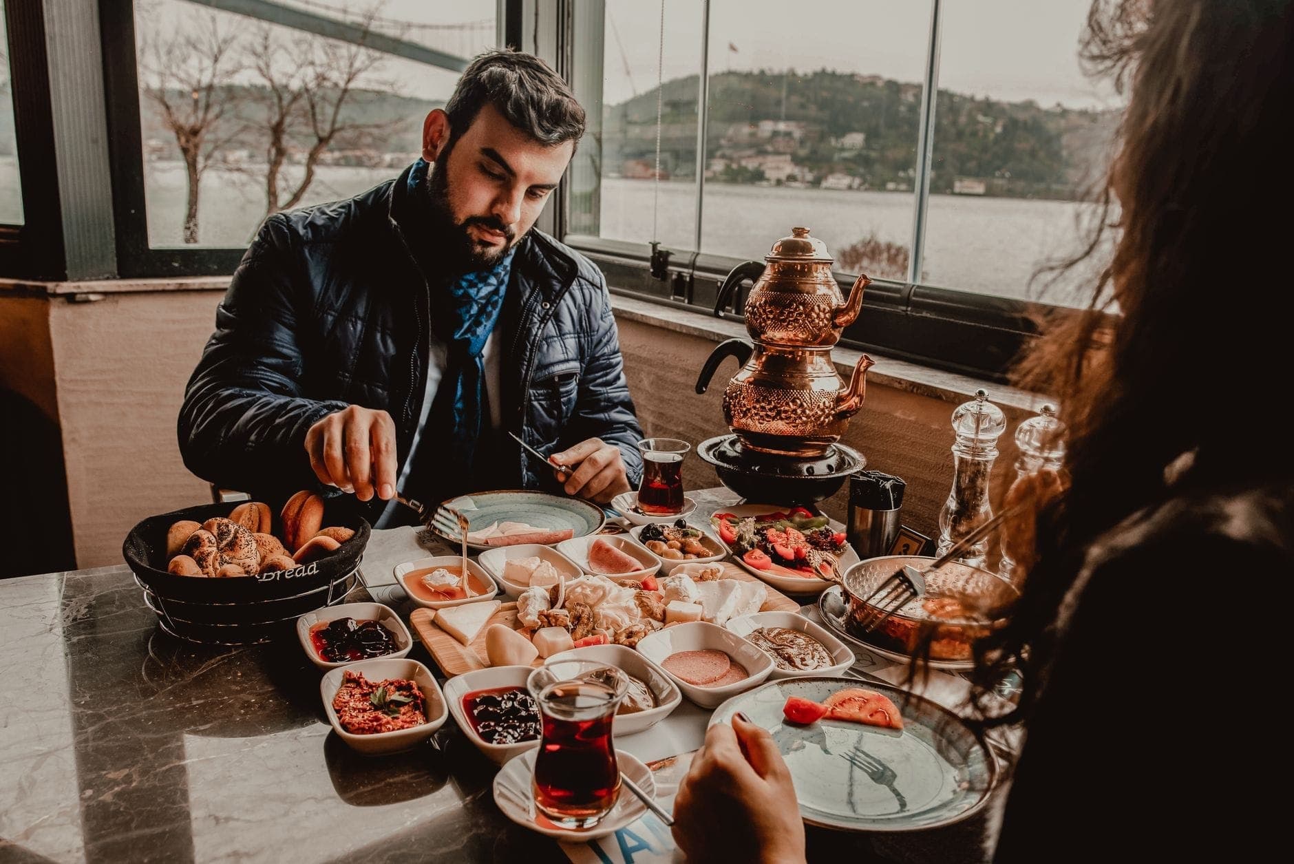 Sarapan Turki tradisional dengan teh di gelas tulip dan samovar, di dekat jendela yang menghadap Bosphorus di Istanbul.