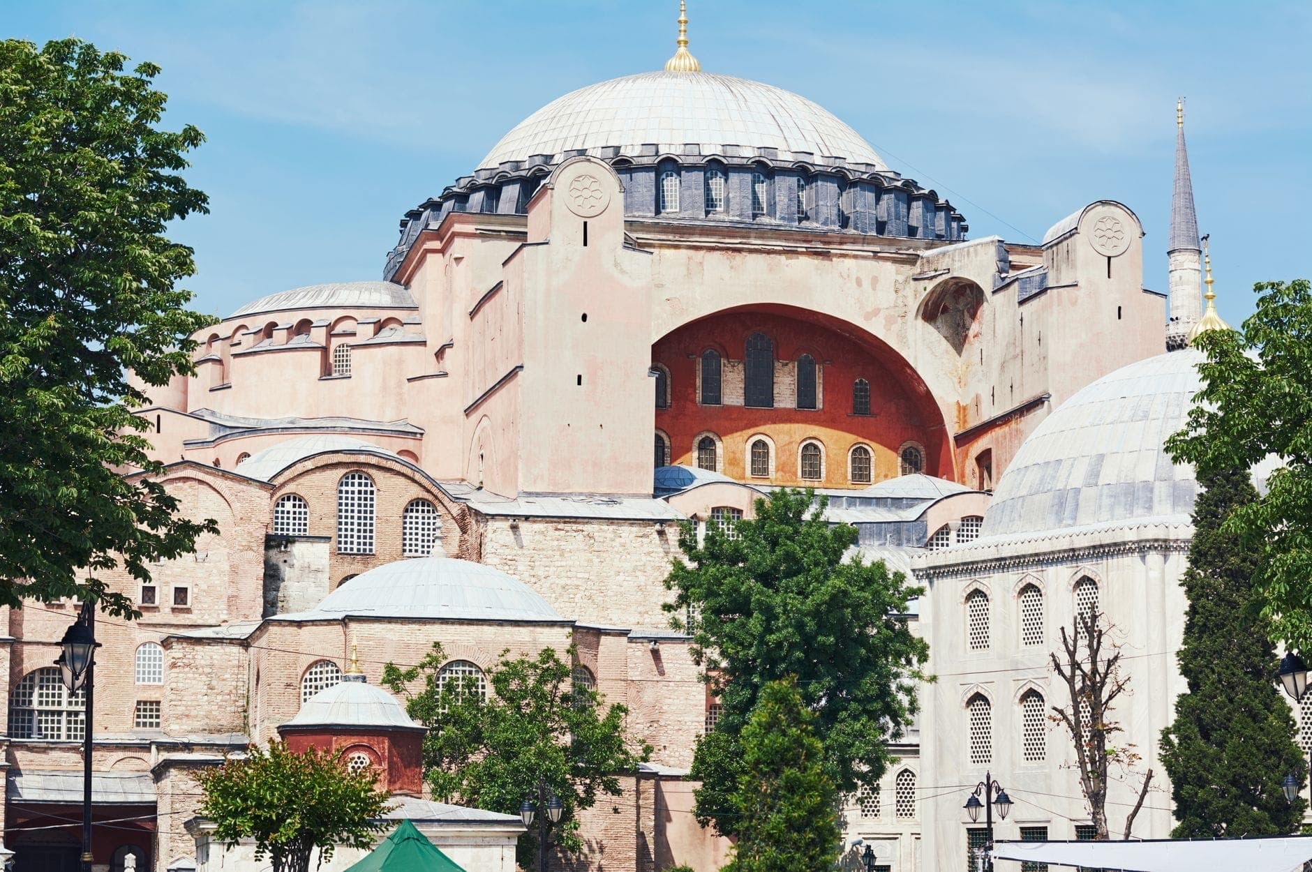 Pemandangan eksterior Hagia Sophia di Istanbul, dengan kubah besar, menara, dan arsitektur bersejarah pada hari yang cerah.
