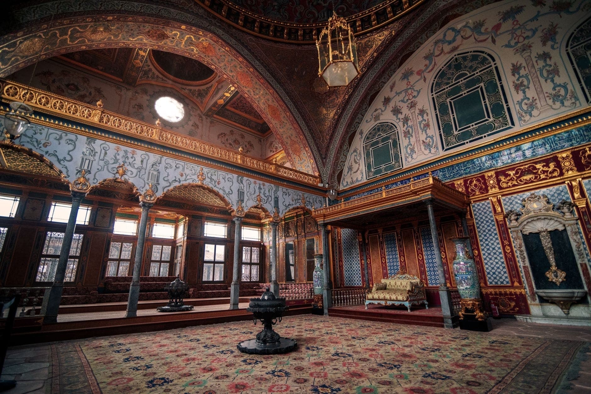 Interior mewah ruang Harem Istana Topkapi dengan hiasan emas, kolom, karpet, dan ubin dekoratif yang indah, menampilkan salah satu atraksi utama yang termasuk dalam Istanbul Museum Pass.