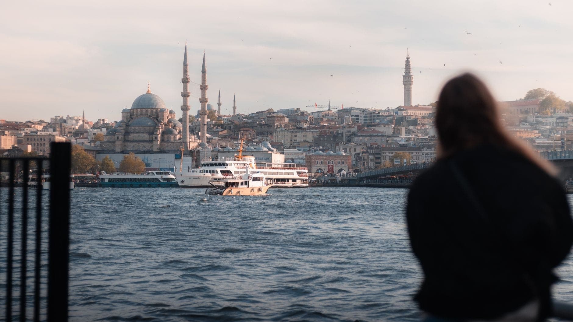 Reisende blicken über den Bosporus auf Istanbuls Skyline mit Moscheen, Minaretten und Fähren – die lebendige Atmosphäre und der historische Charme der Stadt bei Sonnenuntergang.