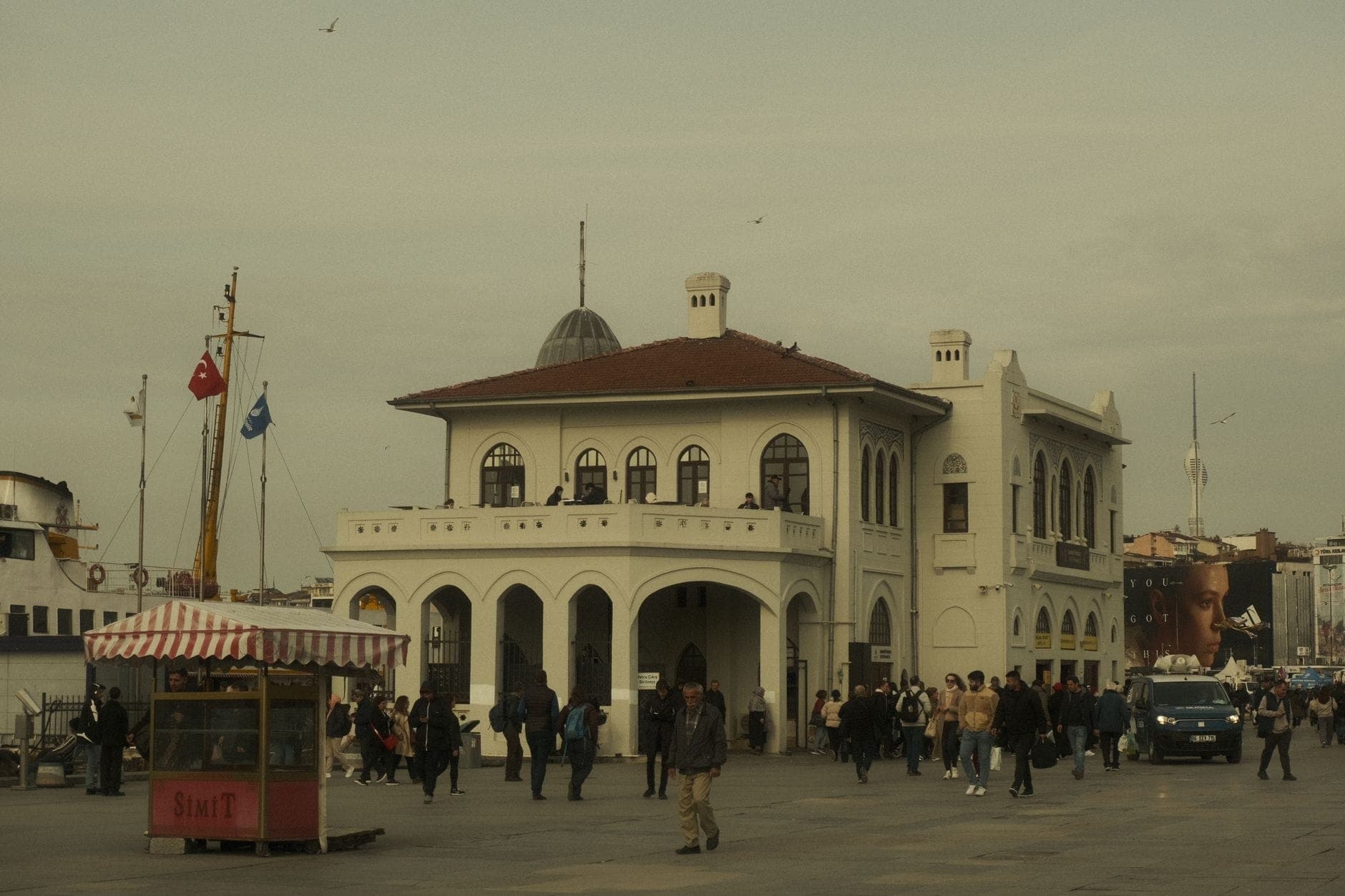 Паромный терминал Kadıköy на азиатской стороне Стамбула: прохожие и тележка с симитом на переднем плане.