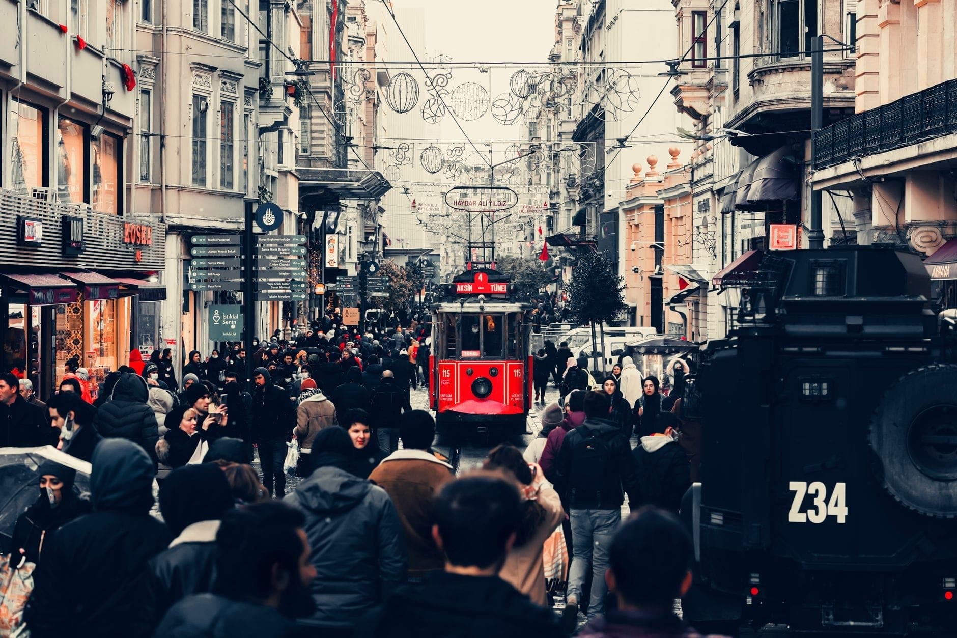 Concurrida calle İstiklal Caddesi en Estambul con multitudes, tiendas y el icónico tranvía rojo en el centro.