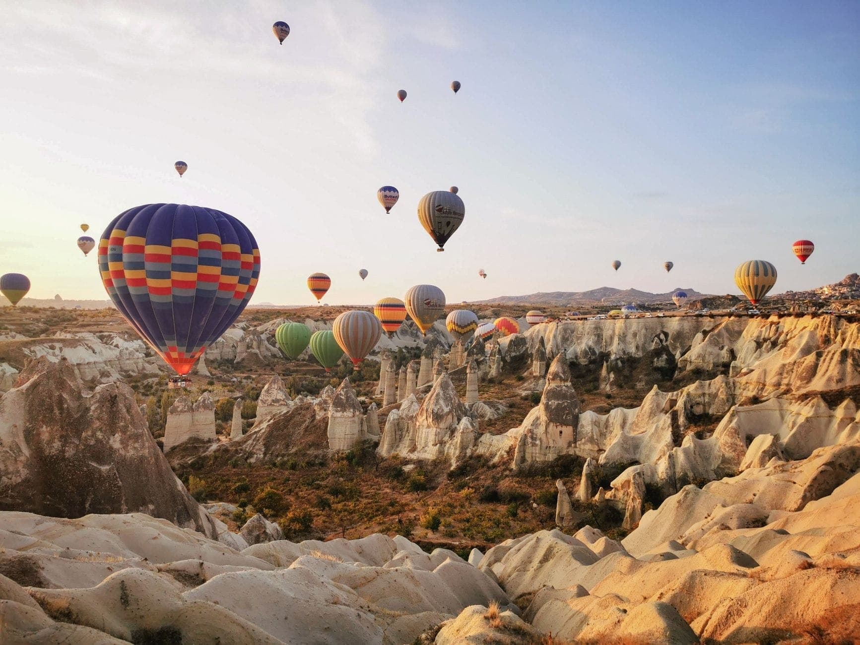 Heißluftballons schweben bei Sonnenaufgang über den markanten Felsformationen und Tälern Kappadokiens – ein eindrucksvolles Bild der einzigartigen Landschaft und des Abenteuerfaktors dieser Region.