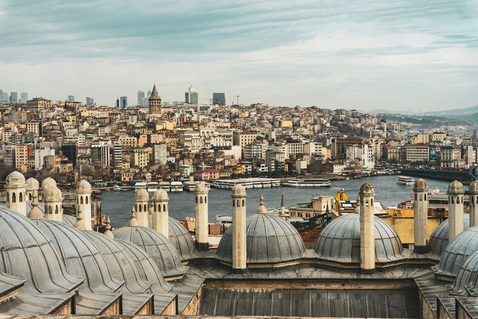Mehrere Kuppeldächer von Moscheen mit einem Panoramablick auf Istanbul und den Bosporus im Hintergrund.