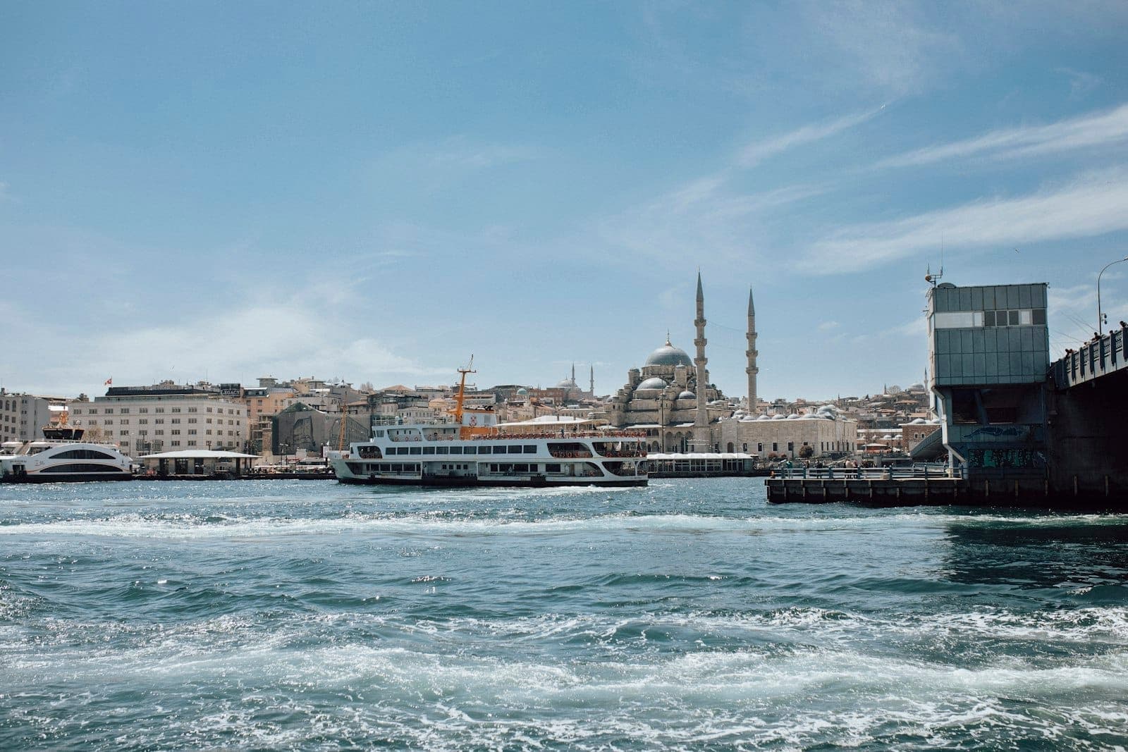 Escena del canal de Estambul con un ferry, el horizonte de mezquitas y edificios de la ciudad bajo un cielo azul despejado, que ilustra un clima ideal para hacer turismo y actividades en barco.