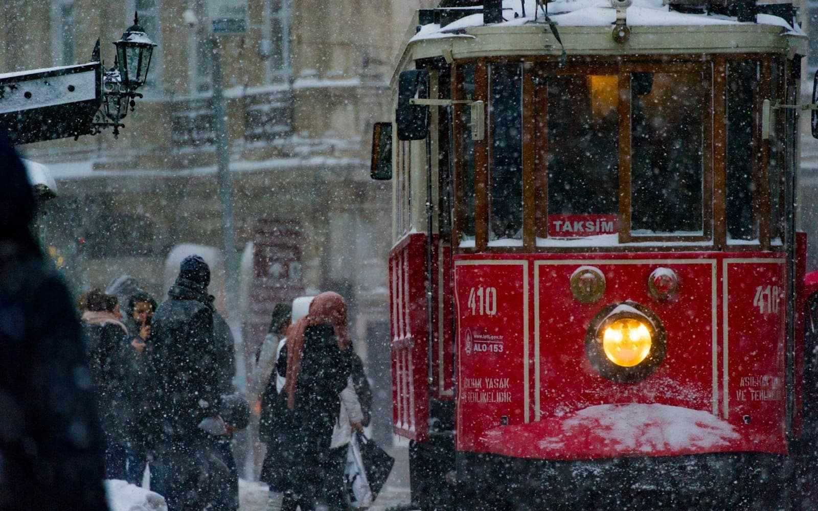 Un tranvía histórico rojo de Estambul avanza entre la nieve con personas abrigadas y copos cayendo en el centro de la ciudad, desmintiendo el mito del calor perpetuo.