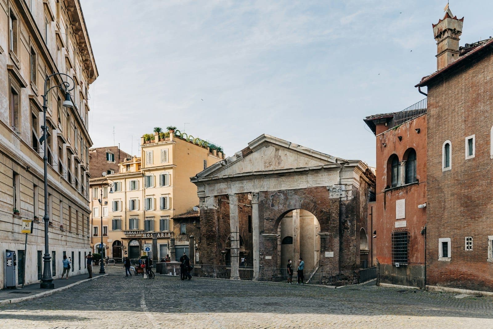 Tanawin ng sinaunang Portico di Ottavia na napapaligiran ng mga makasaysayang gusali sa Jewish Ghetto ng Roma sa isang maliwanag na araw.