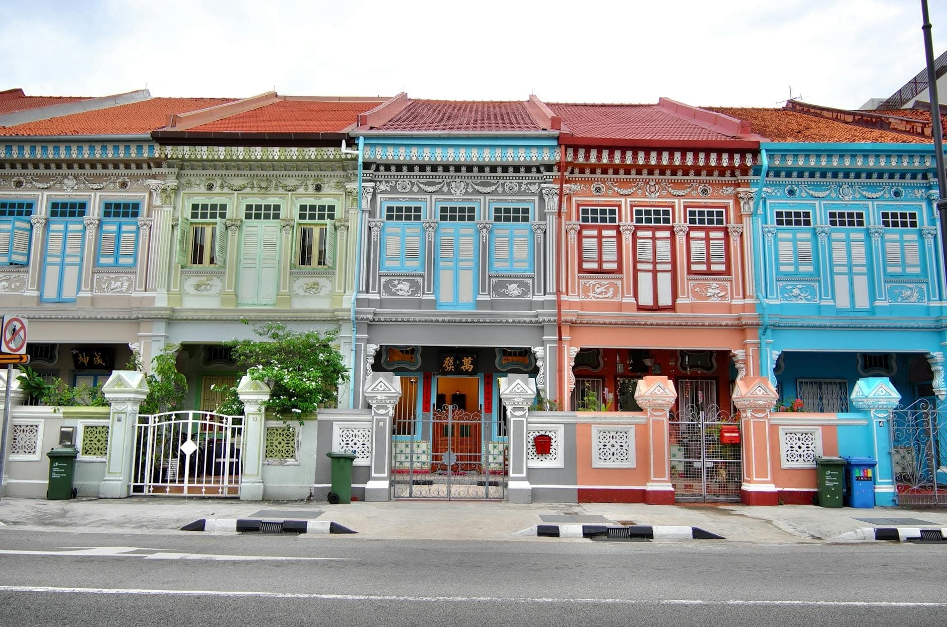 A row of colorful, pastel-painted Peranakan shophouses with ornate facades along a quiet street in Singapore’s Katong or Joo Chiat district.