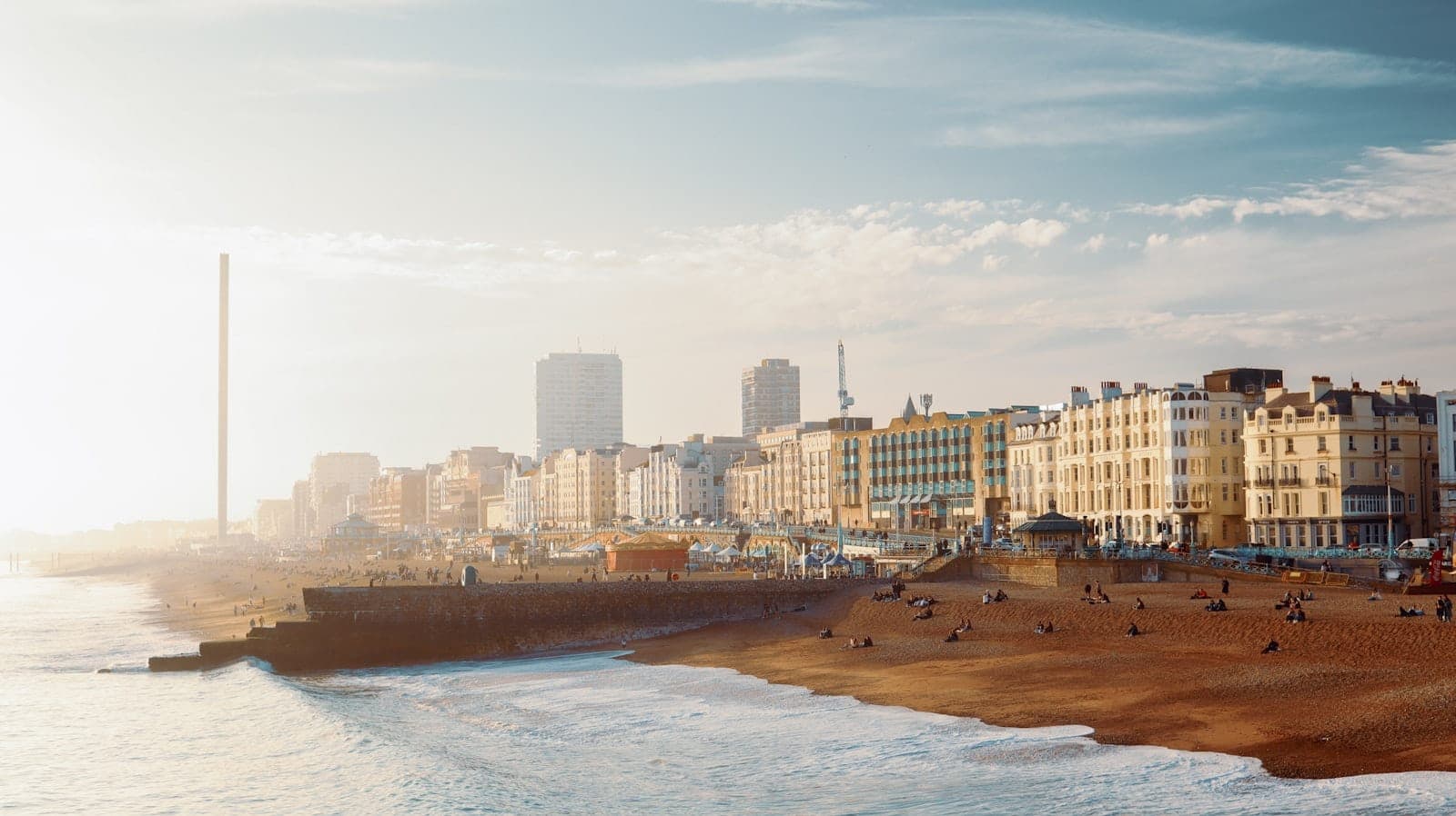Tanaw ang malapad na dalampasigan ng Brighton, mga kilalang Regency building, British Airways i360 tower, at skyline ng lungsod sa ilalim ng liwanag ng araw pagsapit ng dapithapon.