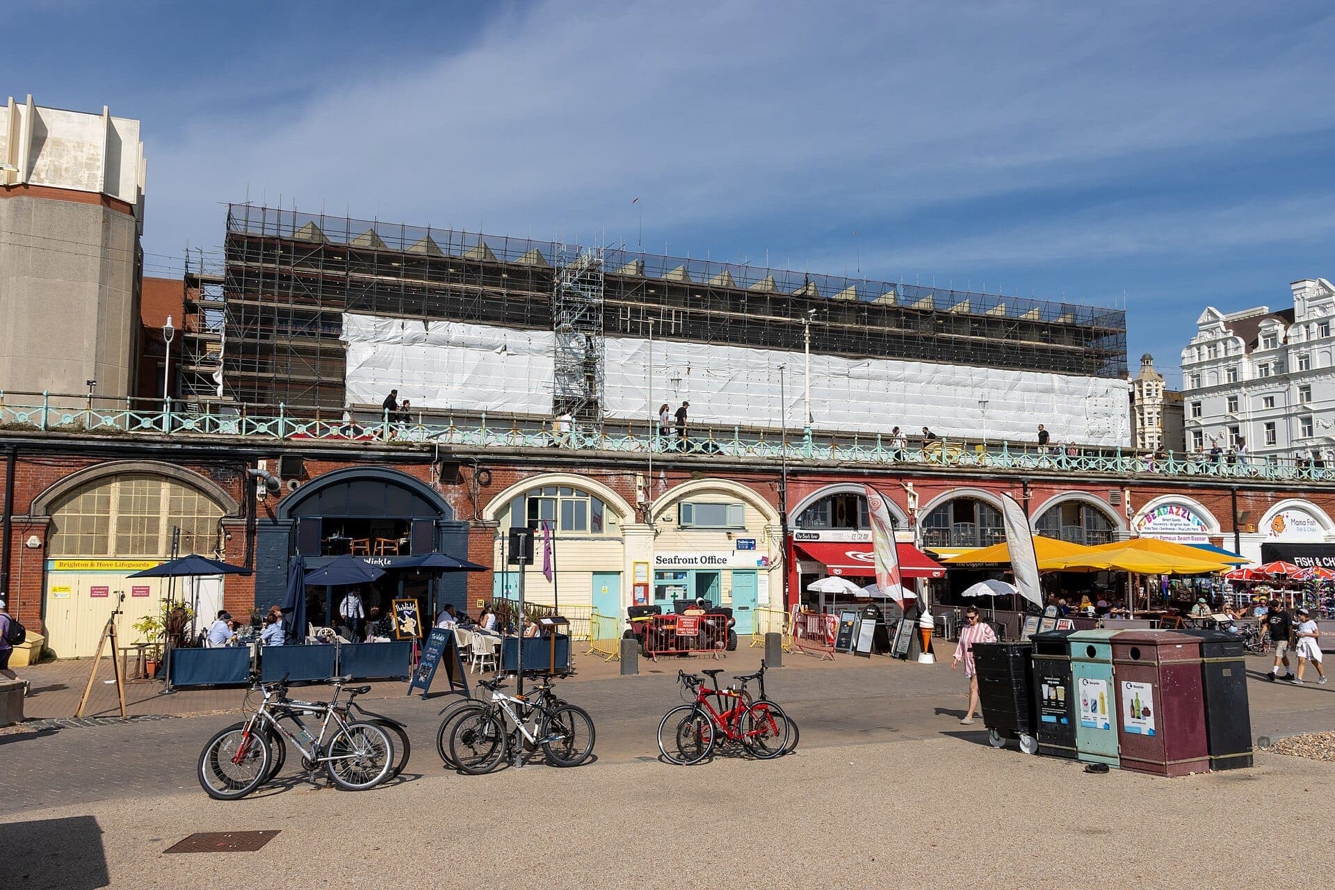 King's Road Arches ở Brighton, hiện ra những vòm gạch bên dưới đường dạo ven biển với các quán cà phê, xe đạp, người đi bộ và bầu trời xanh.