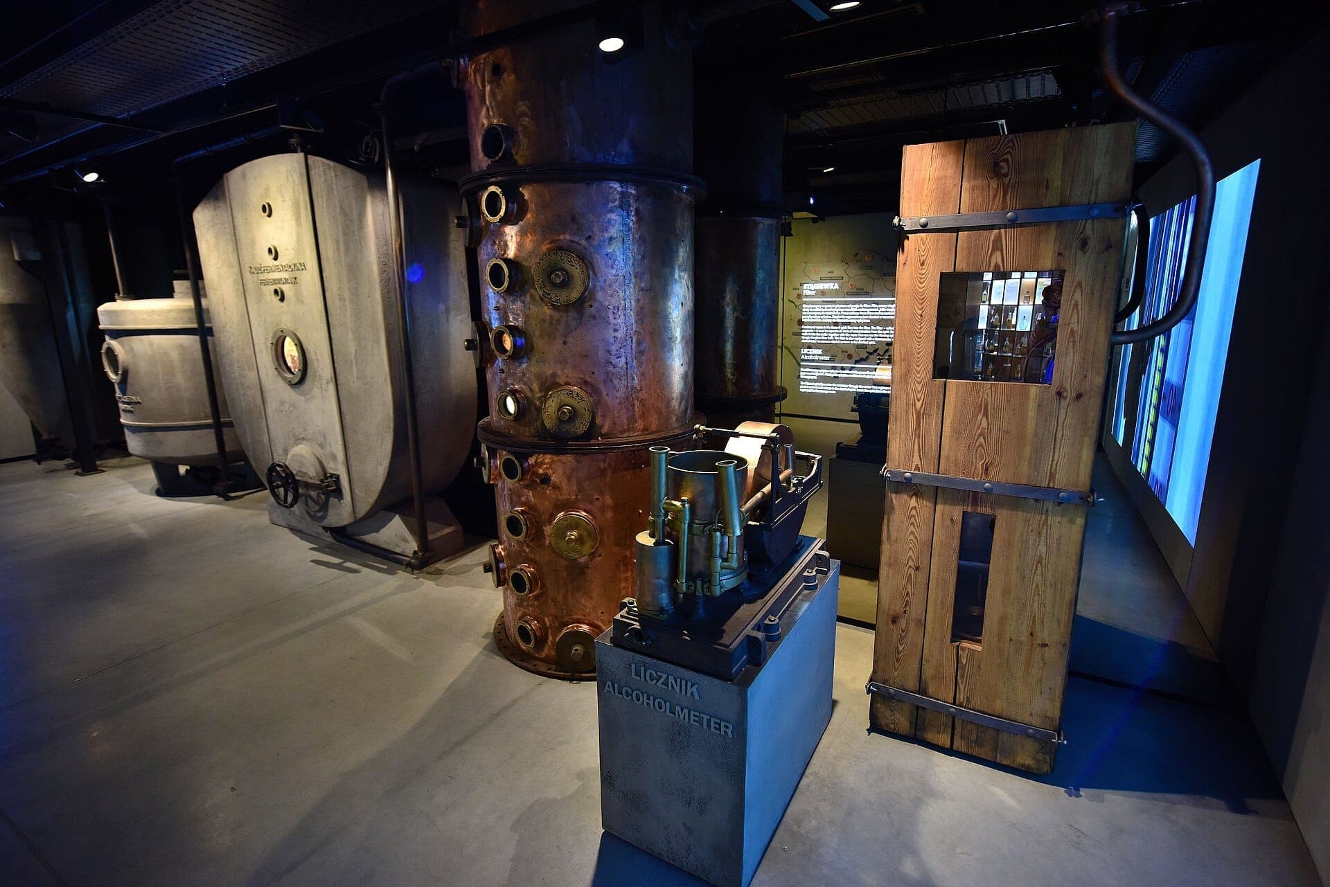 Große Vintage-Destillationstanks und Alkoholmessgeräte in einer schwach beleuchteten Ausstellung im Muzeum Polskiej Wódki, Koneser Center.