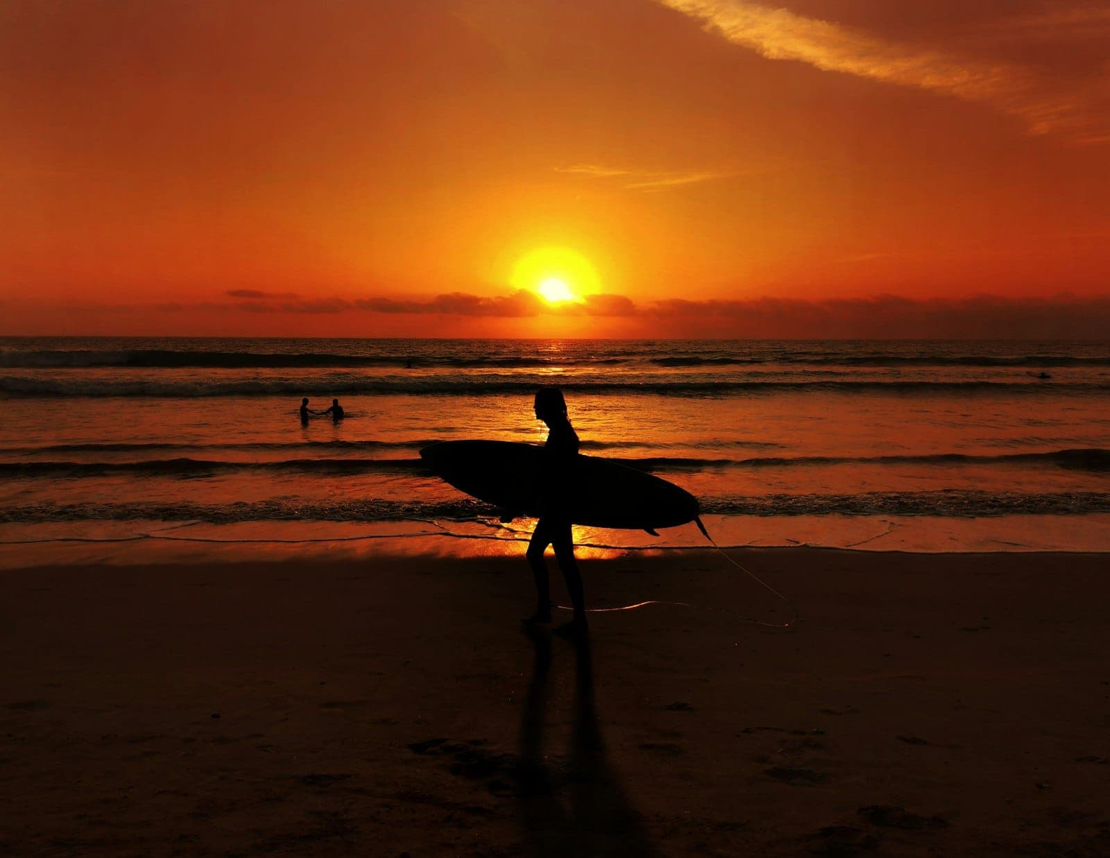 Atmospheric na paglubog ng araw sa Kuta Beach sa Bali, naghahatid ng gintong kulay sa karagatan, at mga silweta ng mga surfer na nagpapaalala sa tahimik na mahika ng tropikal na paraiso