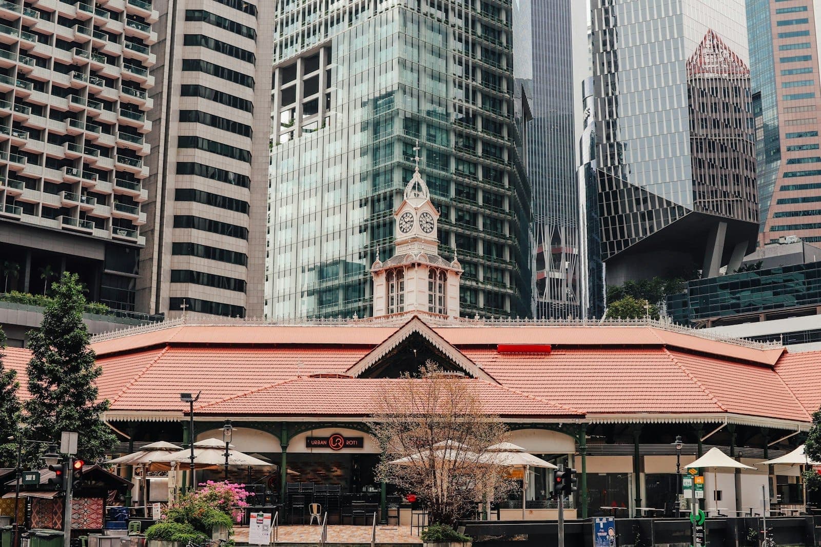 Exterior view of Lau Pa Sat market hall with its distinctive clock tower, set against Singapore’s modern skyscrapers in the financial district.