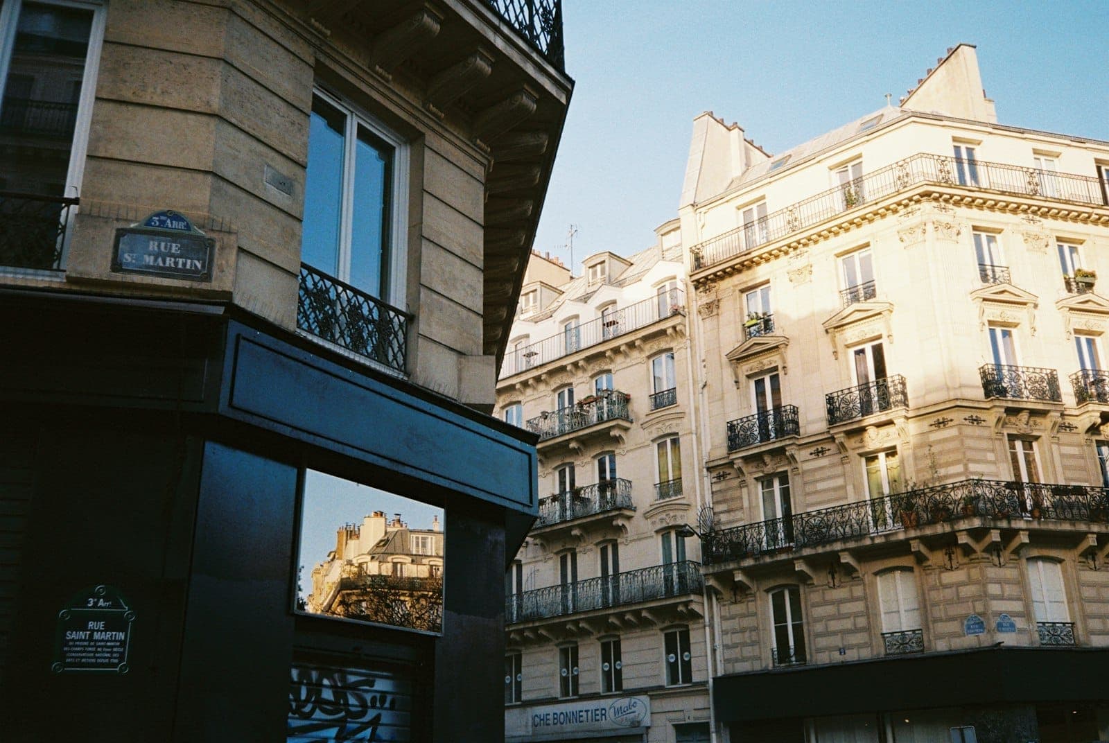 Mga klasikong gusaling Parisian sa distritong Le Marais na nababalutan ng mainit na liwanag ng hapon, may mga palatandaan ng Rue Saint Martin at eleganteng mga harapan, na sumasalamin sa kagandahan ng makasaysayang kapitbahayan.