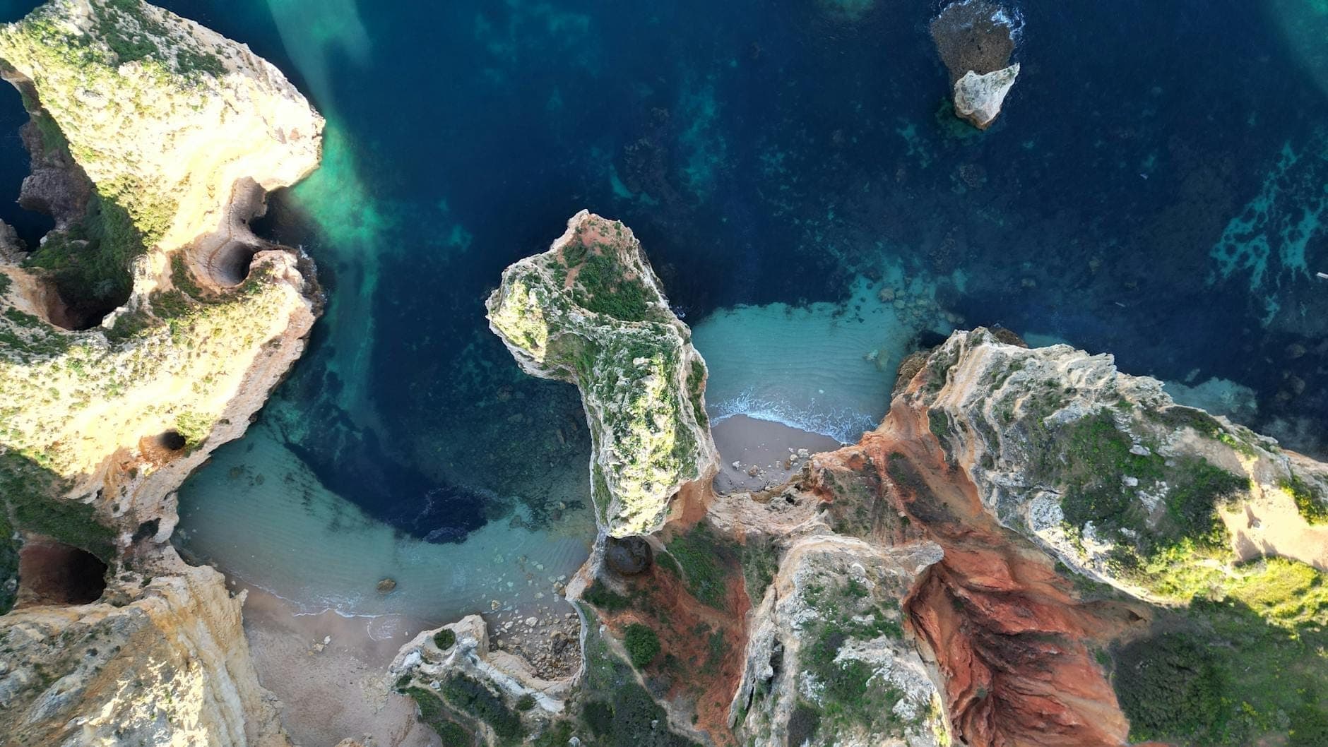 Nhìn từ trên cao xuống đường bờ biển hùng vĩ của Algarve gần Lagos với làn nước xanh trong, vách đá dựng đứng, những vịnh cát nhỏ và thảm cây xanh mướt dưới ánh nắng chói chang.