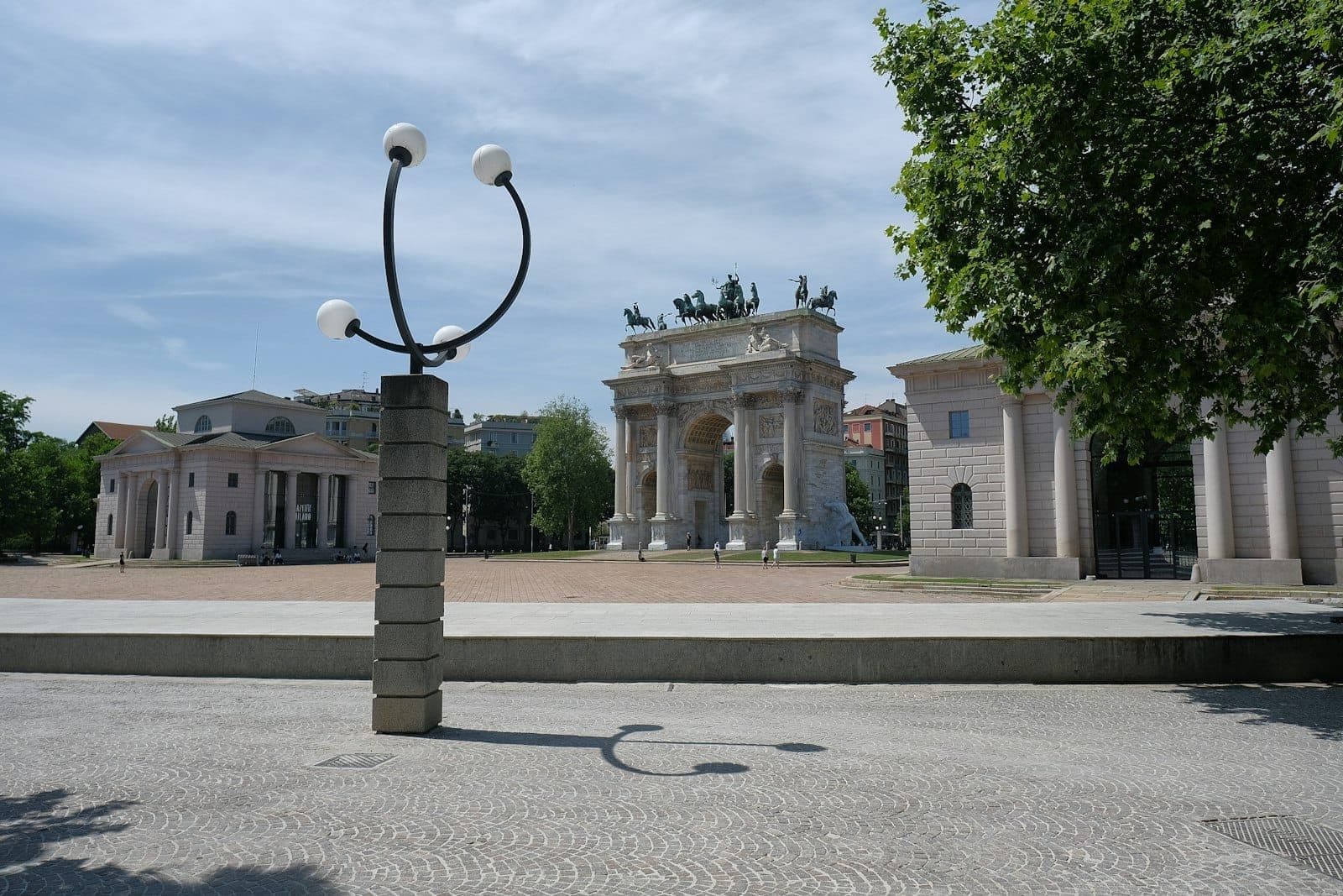 Moderner Laternenpfahl und Mailands Arco della Pace mit umliegenden klassischen Gebäuden bei hellem Tageslicht nahe dem Parco Sempione.