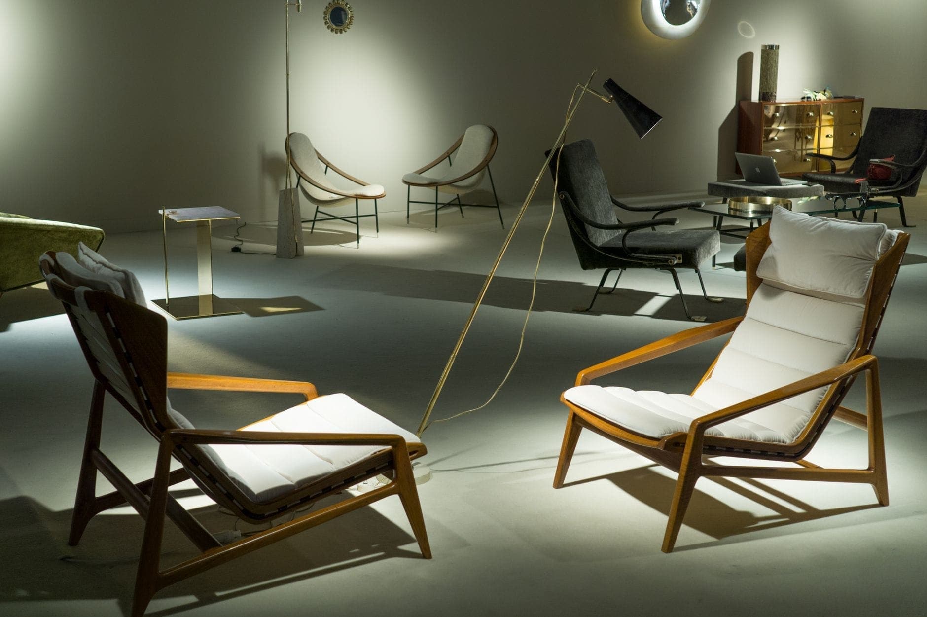 Modern lounge chairs and stylish mid-century furniture are showcased under soft lighting at Milan Design Week Salone del Mobile exhibition space.