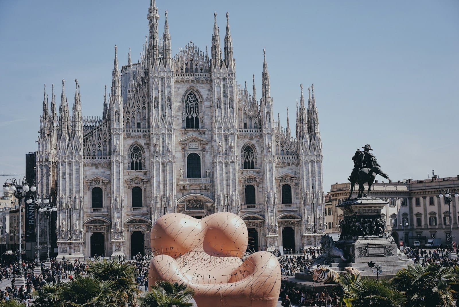 Piazza del Duomo in Mailand mit einer großen modernen Kunstinstallation im Vordergrund während einer belebten öffentlichen Veranstaltung.