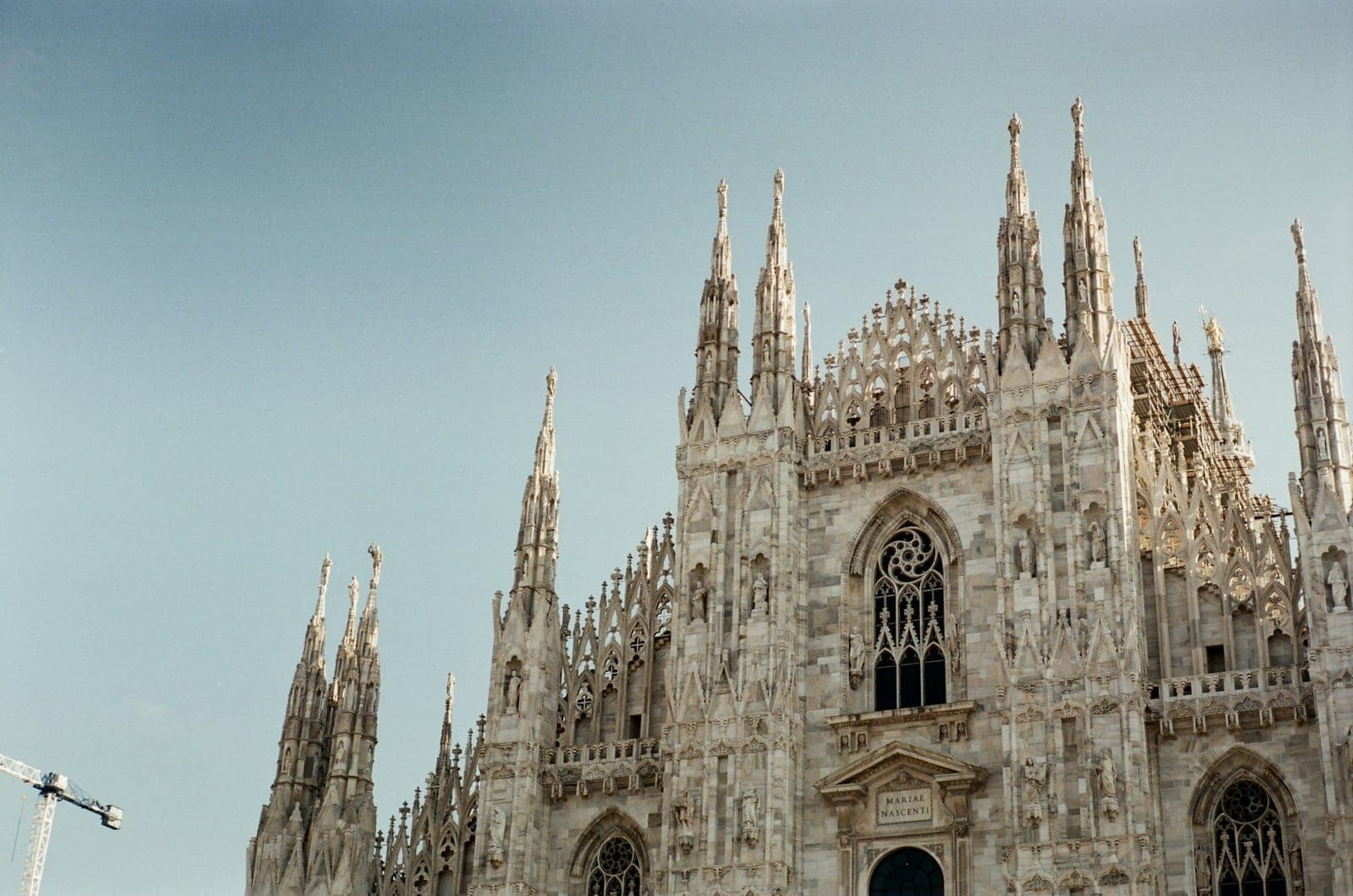 Detailed view of the Milan Cathedral (Duomo di Milano) spires shot against a clear blue sky, highlighting its iconic gothic architecture.