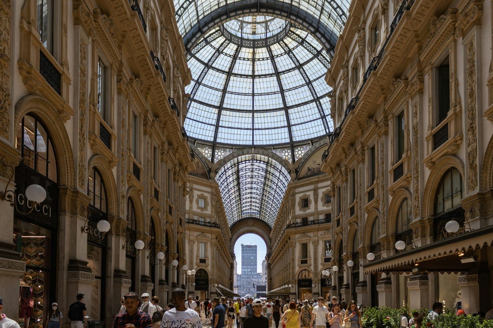 Galleria Vittorio Emanuele II อันหรูหราในมิลานที่มีหลังคากระจก เต็มไปด้วยผู้คนและร้านค้าชั้นสูงอย่าง Gucci สะท้อนชื่อเสียงของมิลานในฐานะเมืองหลวงแห่งแฟชั่นระดับโลก