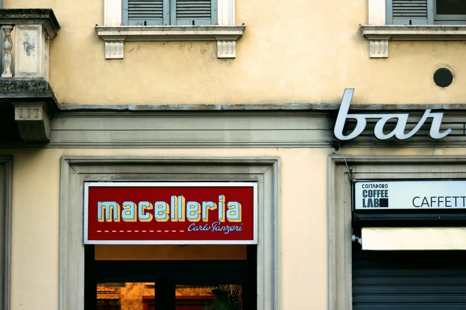 Vetrina di una macelleria e bar in una via di Milano, che mostra la tradizione culinaria a base di carne della Lombardia.