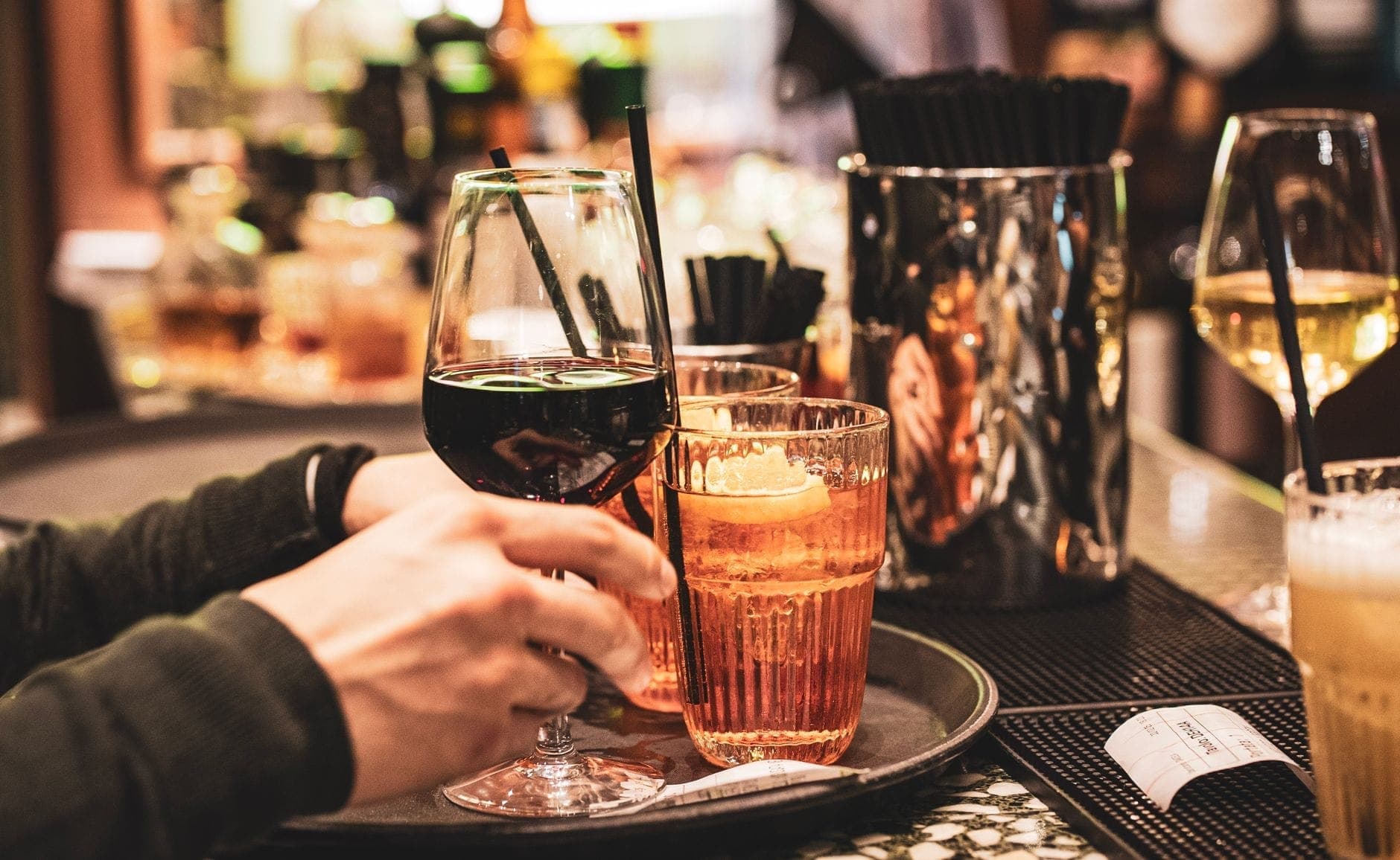 Gläser mit italienischen Cocktails, darunter Aperol Spritz und Wein, auf einem Bartablett, kurz vor dem Servieren in einer stilvollen Mailänder Bar.