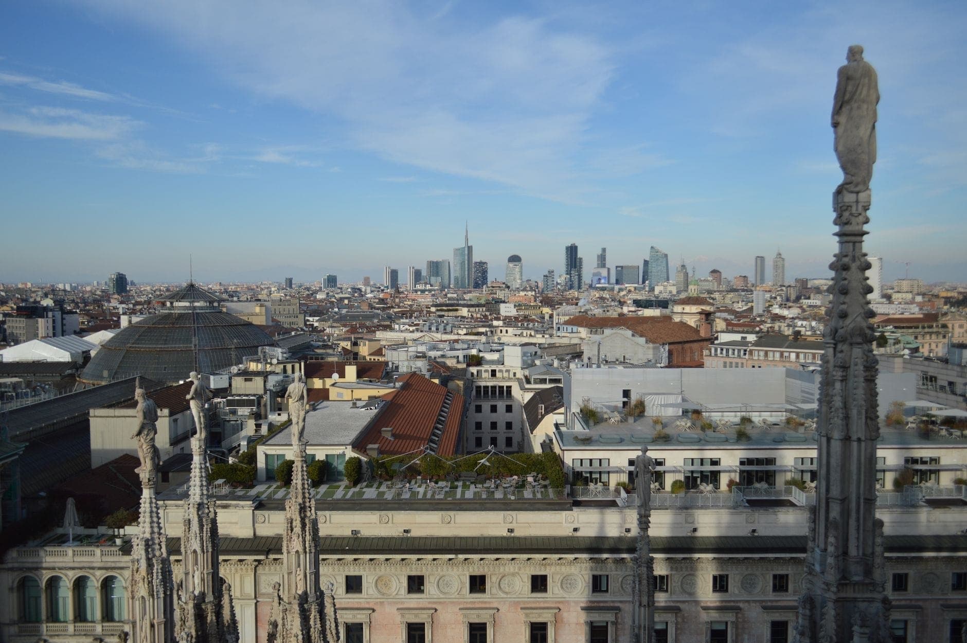 Vista soleada desde la azotea del Duomo de Milán con el horizonte de la ciudad y las agujas de la catedral, que ilustra el agradable clima primaveral y una popular atracción para toda la familia.