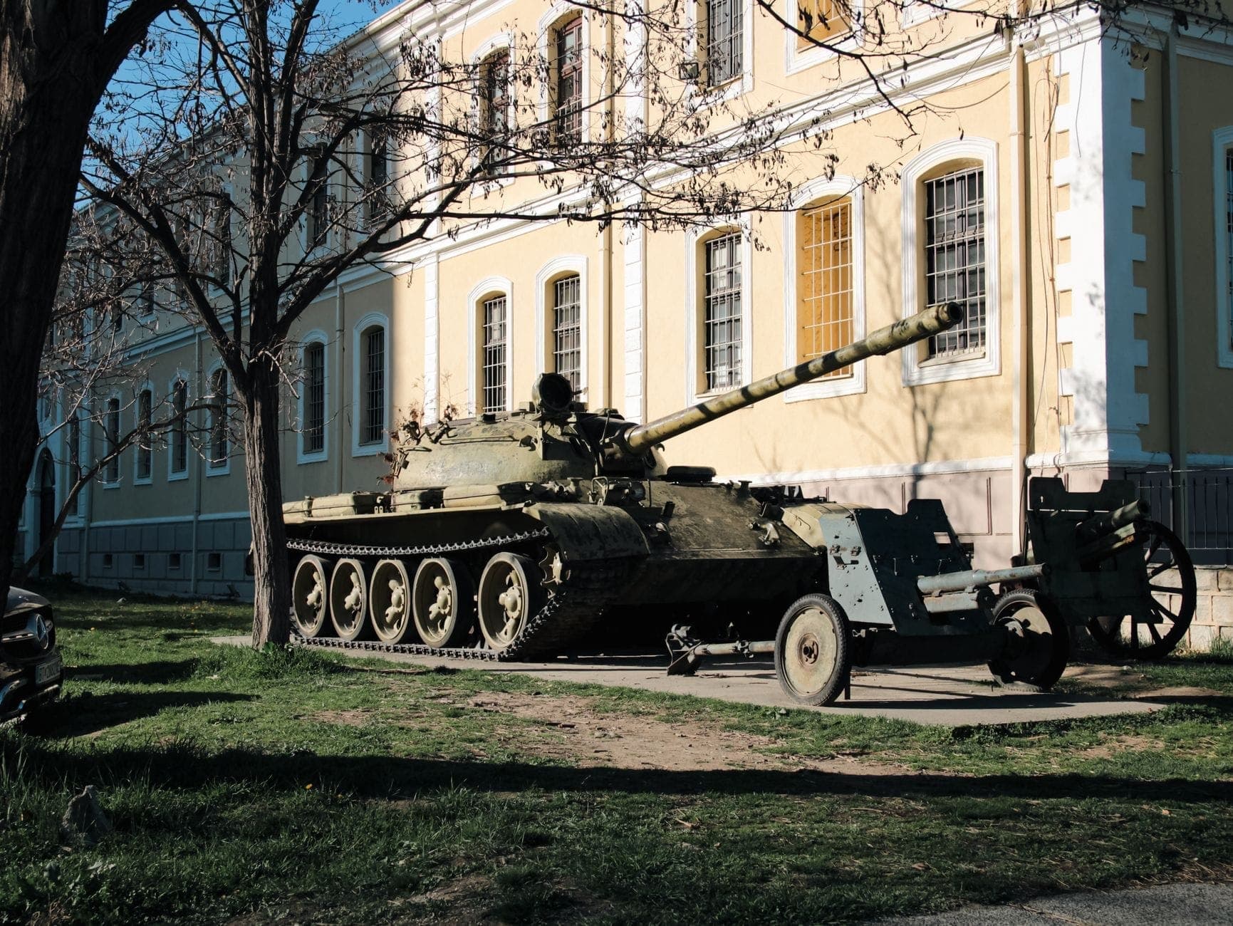 Ein Panzer vor dem Istanbuler Militärmuseum im Freien, mit der gelblichen historischen Fassade des Gebäudes und Militärausrüstung bei klarem Tageslicht.
