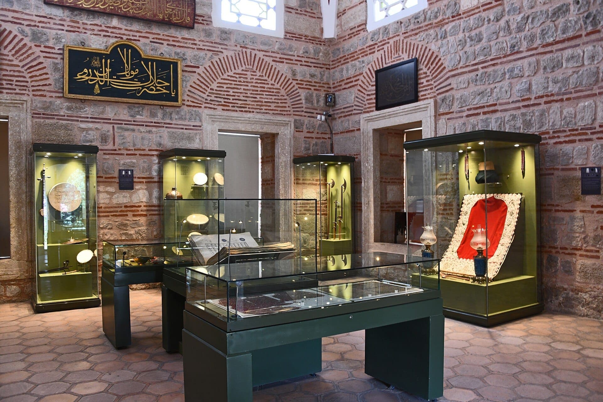 Ausstellungsraum im Museum of Turkish and Islamic Arts mit Exponaten in Glasvitrinen vor historischen osmanischen Stein- und Backsteinwänden.