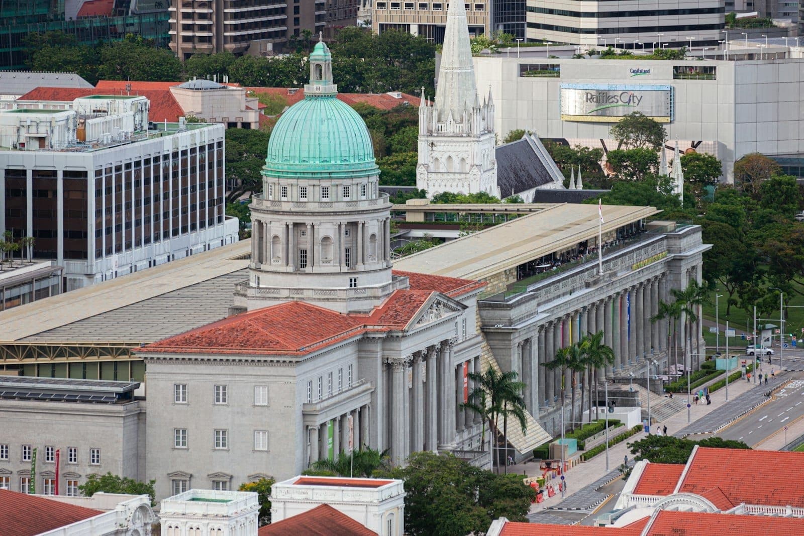 Aerial view of National Gallery Singapore, showcasing its grand colonial architecture with a green dome, classical columns, and surrounding city buildings.
