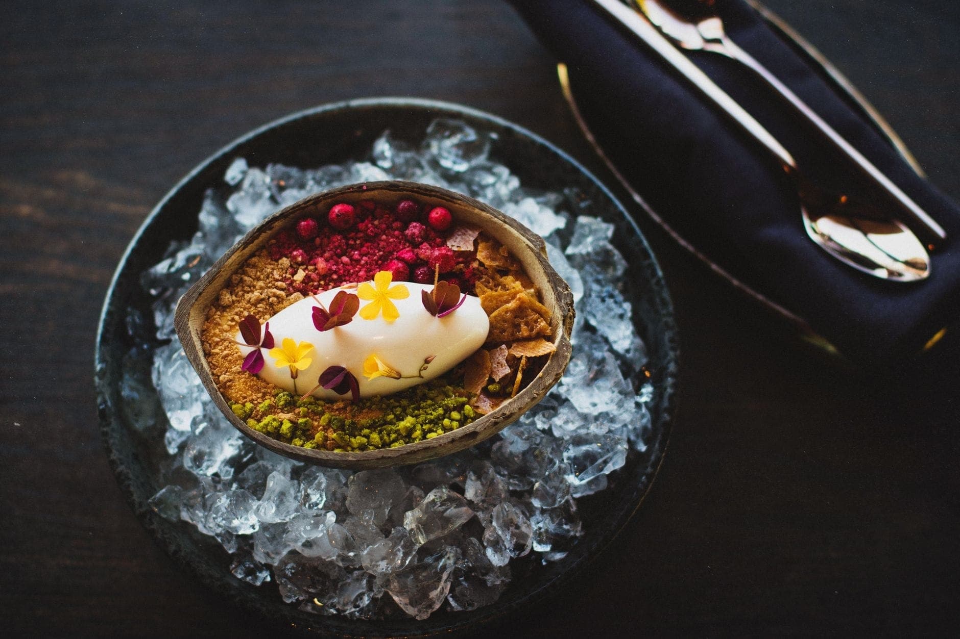 Ein kunstvoll angerichtetes nordisches Dessert mit Eis, essbaren Blüten und Beeren, serviert in einer Eisschüssel — das verkörpert Kopenhagens modernen Küchenstil.