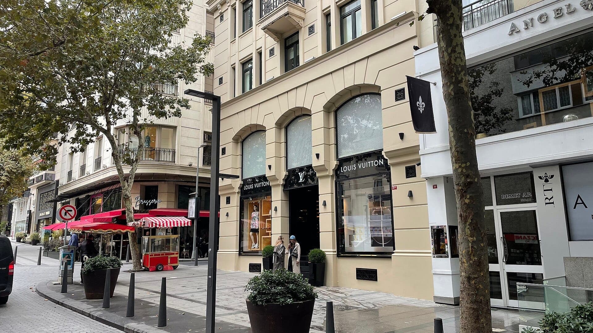 Straßenansicht von Nişantaşı in Şişli, Istanbul, mit exklusiven Boutiquen, einem Louis Vuitton-Geschäft und Menschen, die auf einem baumgesäumten Gehweg spazieren.