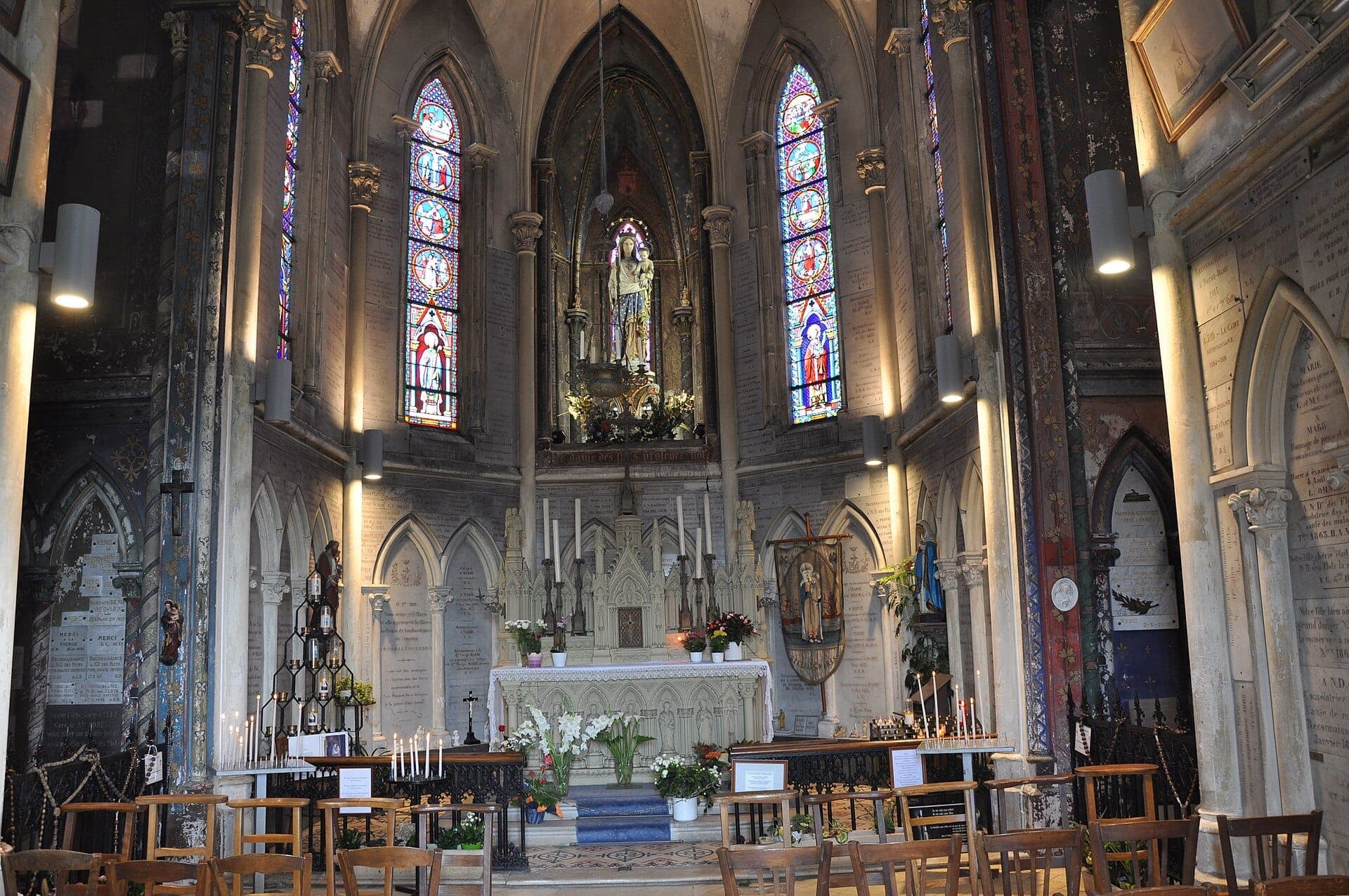 Nội thất của Chapelle Notre-Dame-des-Flots với kiến trúc tân Gothic trang trí tinh xảo, cửa sổ kính màu, ghế gỗ và nhiều ngọn nến sáng gần bàn thờ.