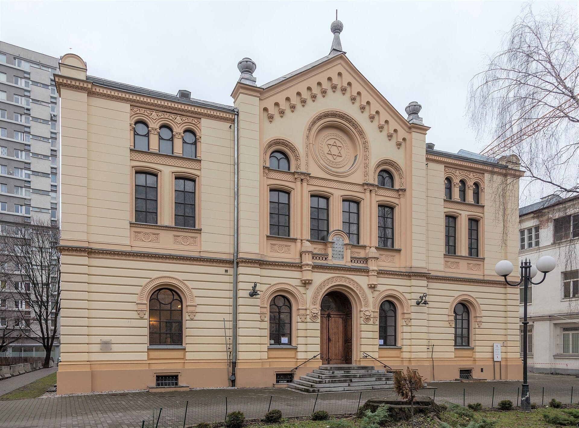 Frontansicht der Nożyk-Synagoge in Warschau mit ihrer gelb-beigen Fassade, Bogenfenstern und einem detaillierten Davidstern über dem Eingang.