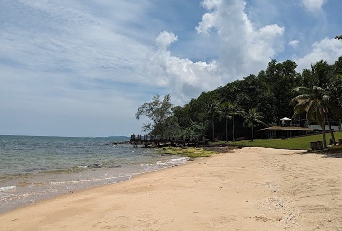 Dalampasigan sa Ong Lang Phu Quoc na may ginintuang buhangin, kalmadong dagat, at baybaying niyugan malapit sa tahimik na pantalan