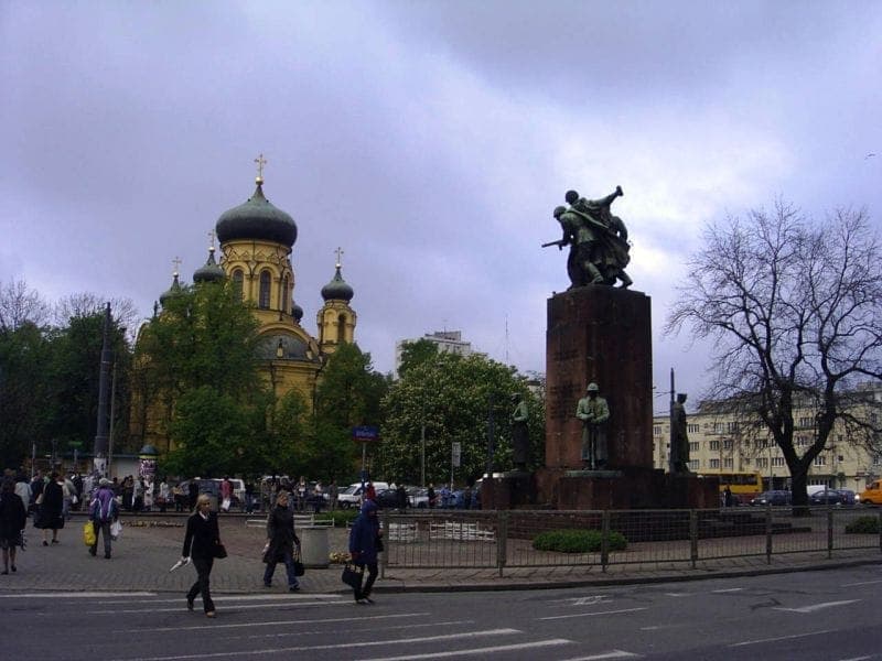 Die Orthodoxe Kathedrale der Heiligen Maria Magdalena mit ihren goldenen Zwiebelkuppeln erhebt sich hinter einem Denkmal in einer belebten Straßenszene in Warschau.