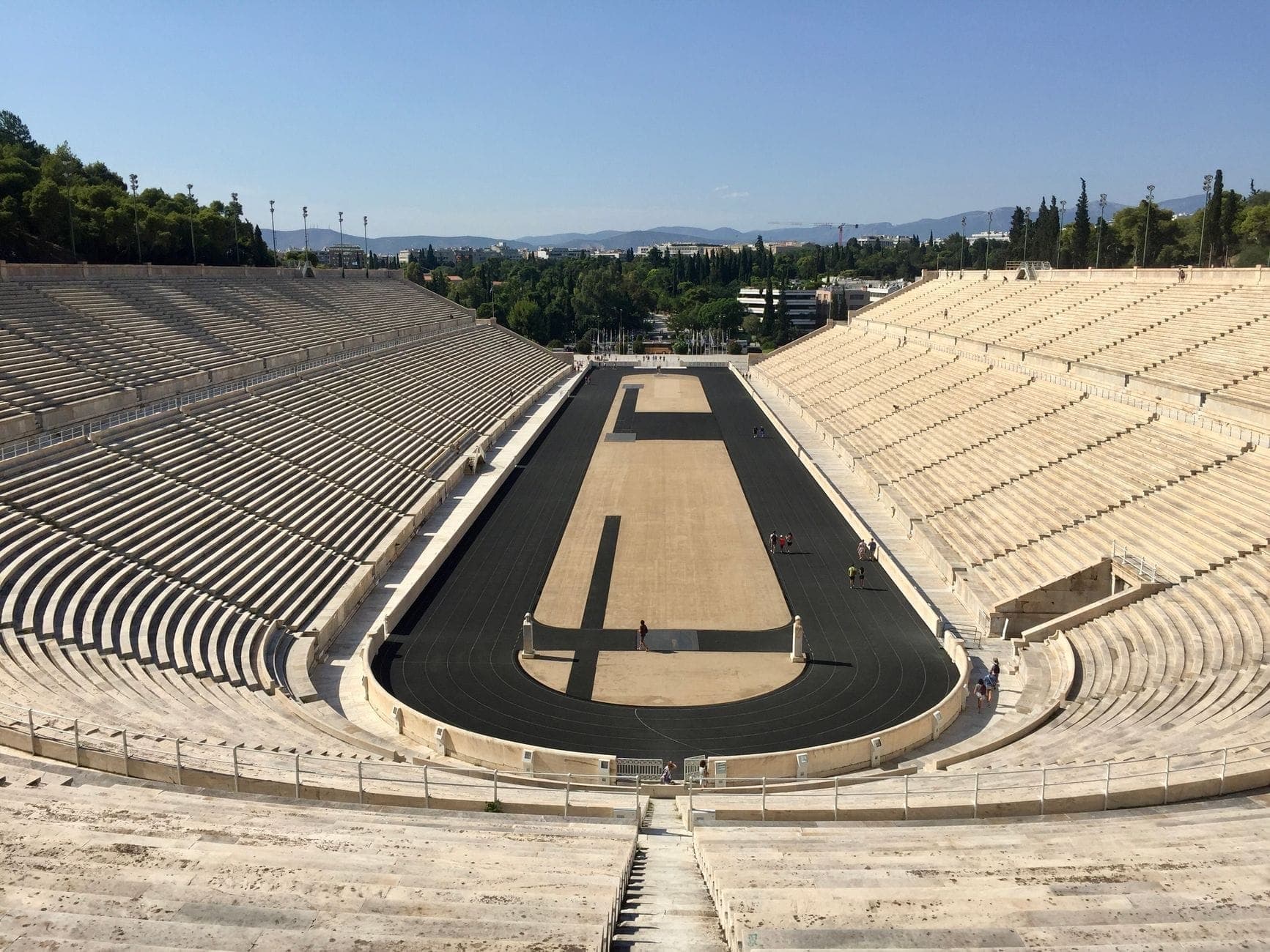 Wide-angle view of the Panathenaic Stadium, showing the marble stands and black running track under a clear blue sky, capturing the stadium’s full grandeur.