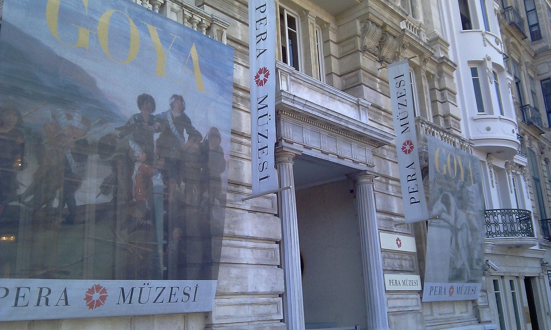 Fassade des Pera Museum in Istanbul mit klassischer Architektur, großen Bannern für eine Goya-Ausstellung und Schildern mit der Aufschrift 'Pera Müzesi' auf Türkisch.