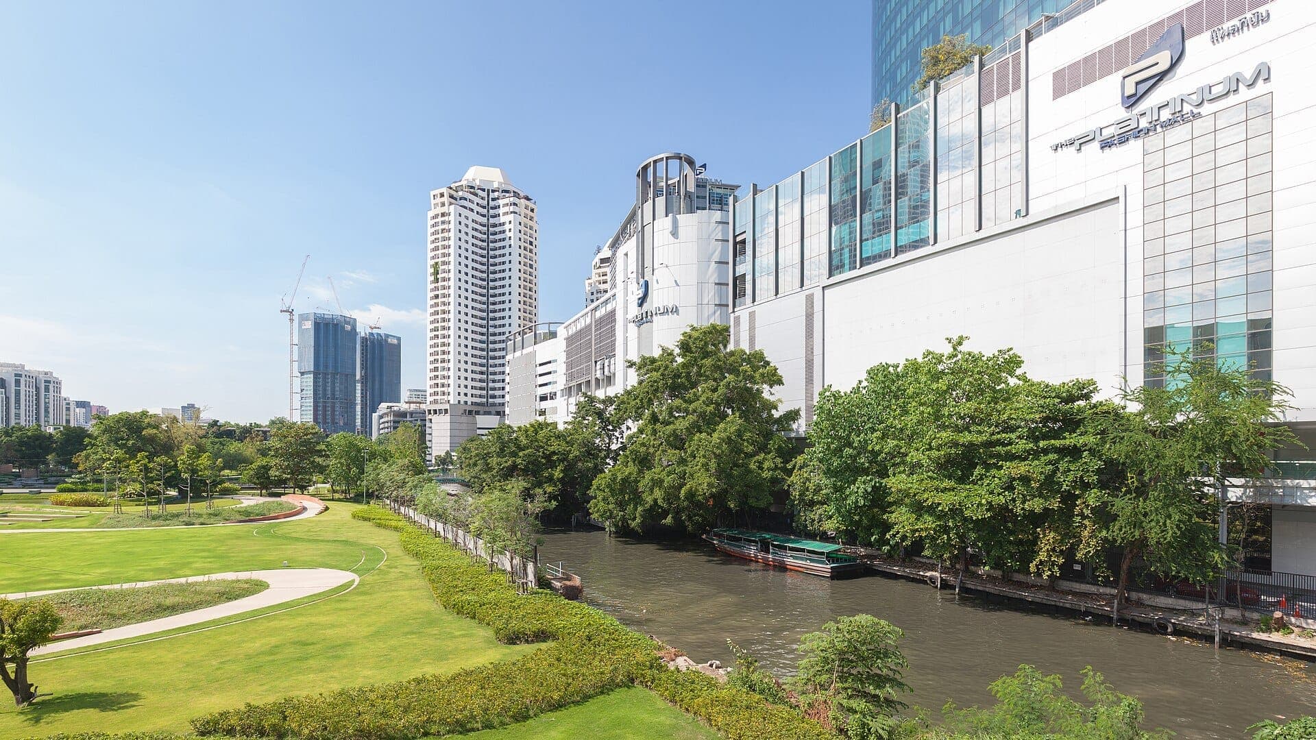 Platinum Fashion Mall ở Bangkok nhìn từ phía kênh với công viên, cây xanh và đường chân trời Pratunam