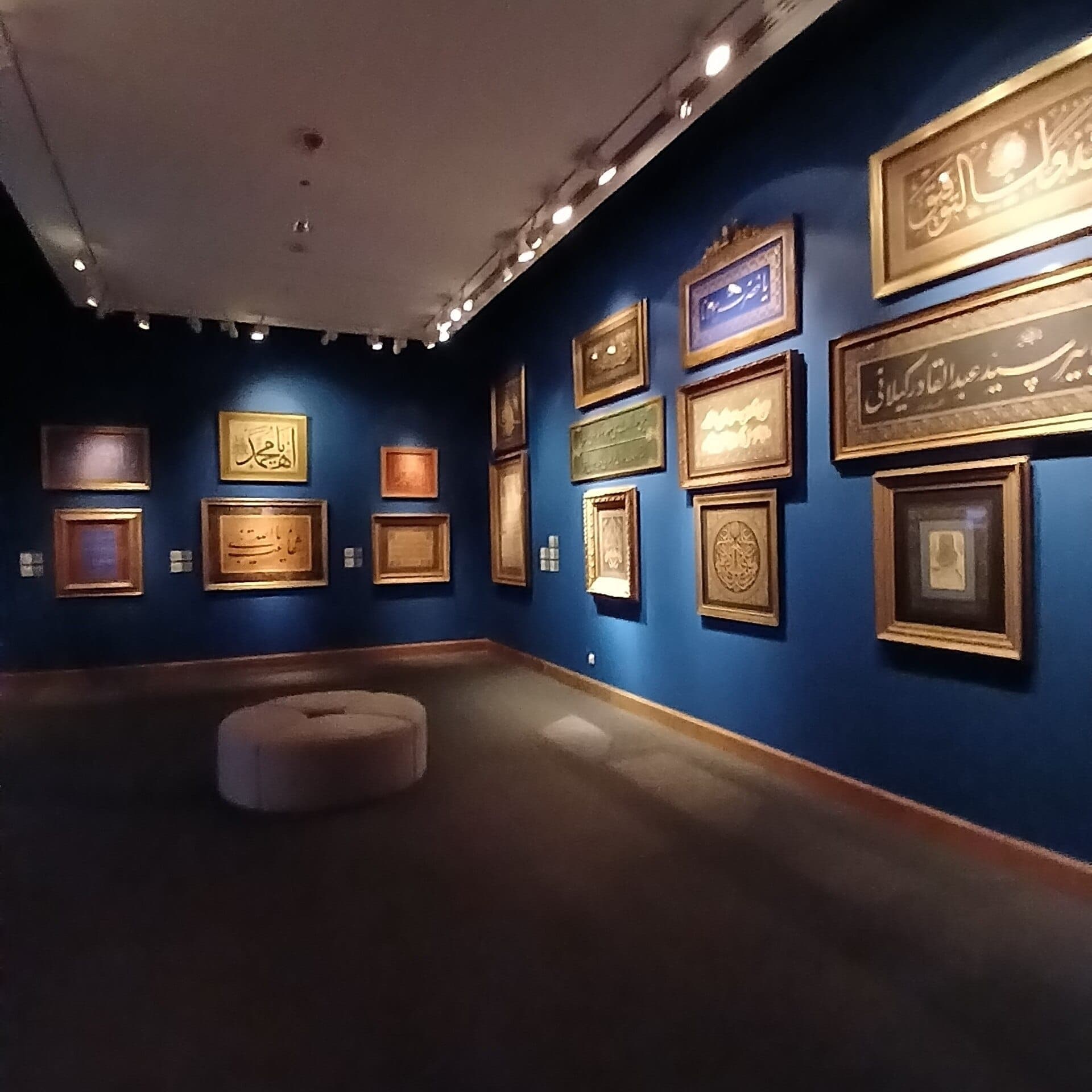 Gerahmte osmanische Kalligrafiewerke an tiefblauen Wänden in einer sanft beleuchteten Galerie des Sakıp Sabancı Müzesi in Istanbul.