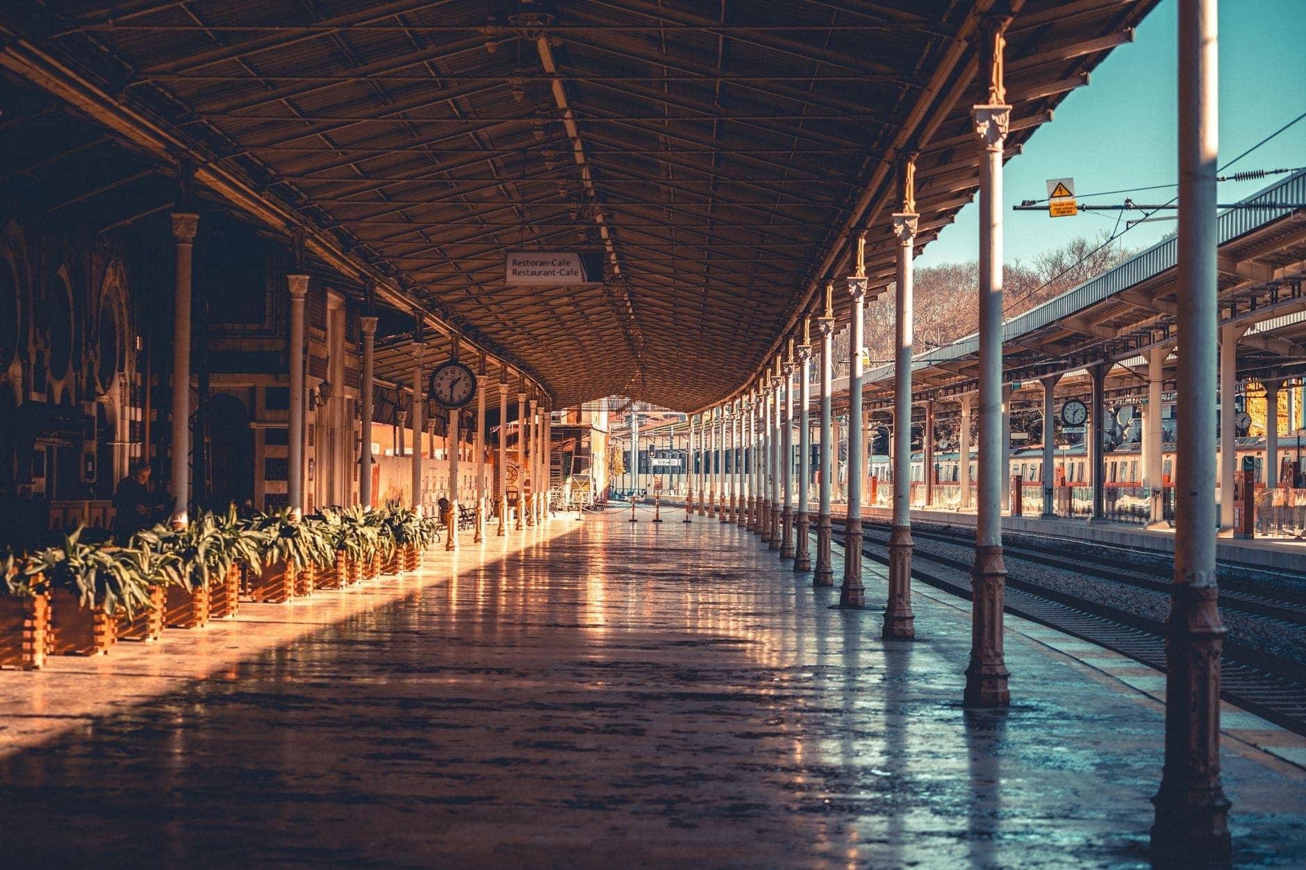 Sonnenbeschiener Bahnsteig des Bahnhofs Sirkeci mit verzierten Säulen, einer Vintage-Uhr und Gleisen, die in die Ferne führen – eine Atmosphäre, die die legendäre Geschichte des Bahnhofs spürbar macht.