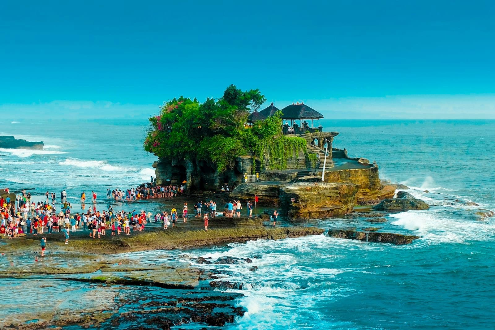 Đền biển Tanah Lot lúc thủy triều thấp với du khách đi bộ qua các tảng đá ven biển, Bali