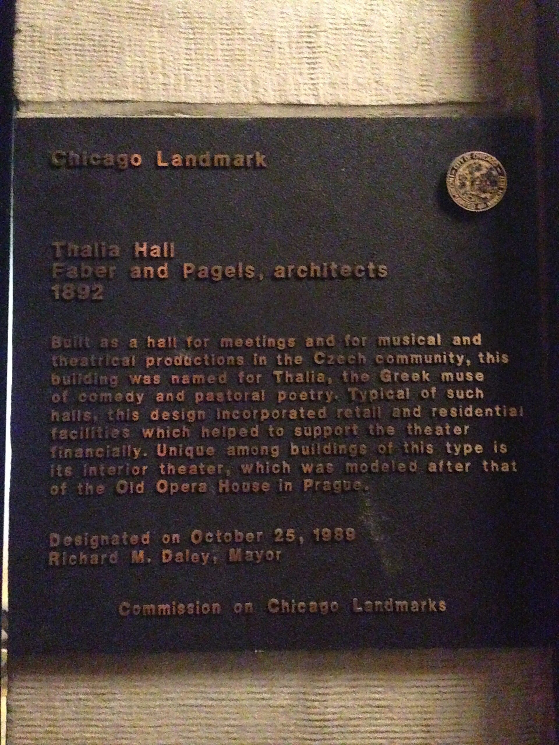 Bronzeplakette des Chicago Landmark für die Thalia Hall, mit Text über ihre Entstehung im Jahr 1892 und ihre architektonische Bedeutung, montiert an einer strukturierten Steinwand.