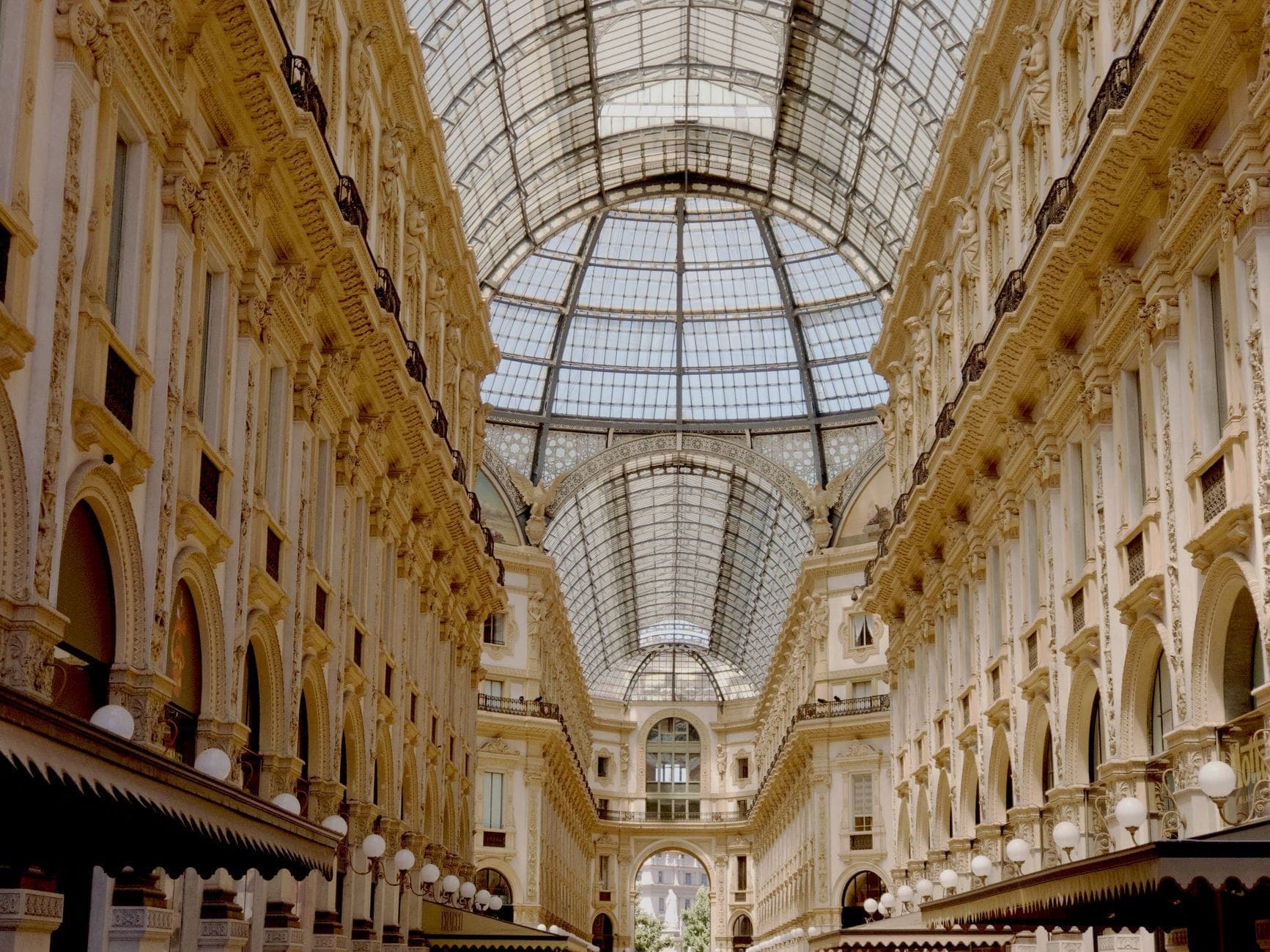 Vista interior amplia de la Galleria Vittorio Emanuele II de Milán, con su ornamentado techo de cristal arqueado y su elegante arquitectura histórica.