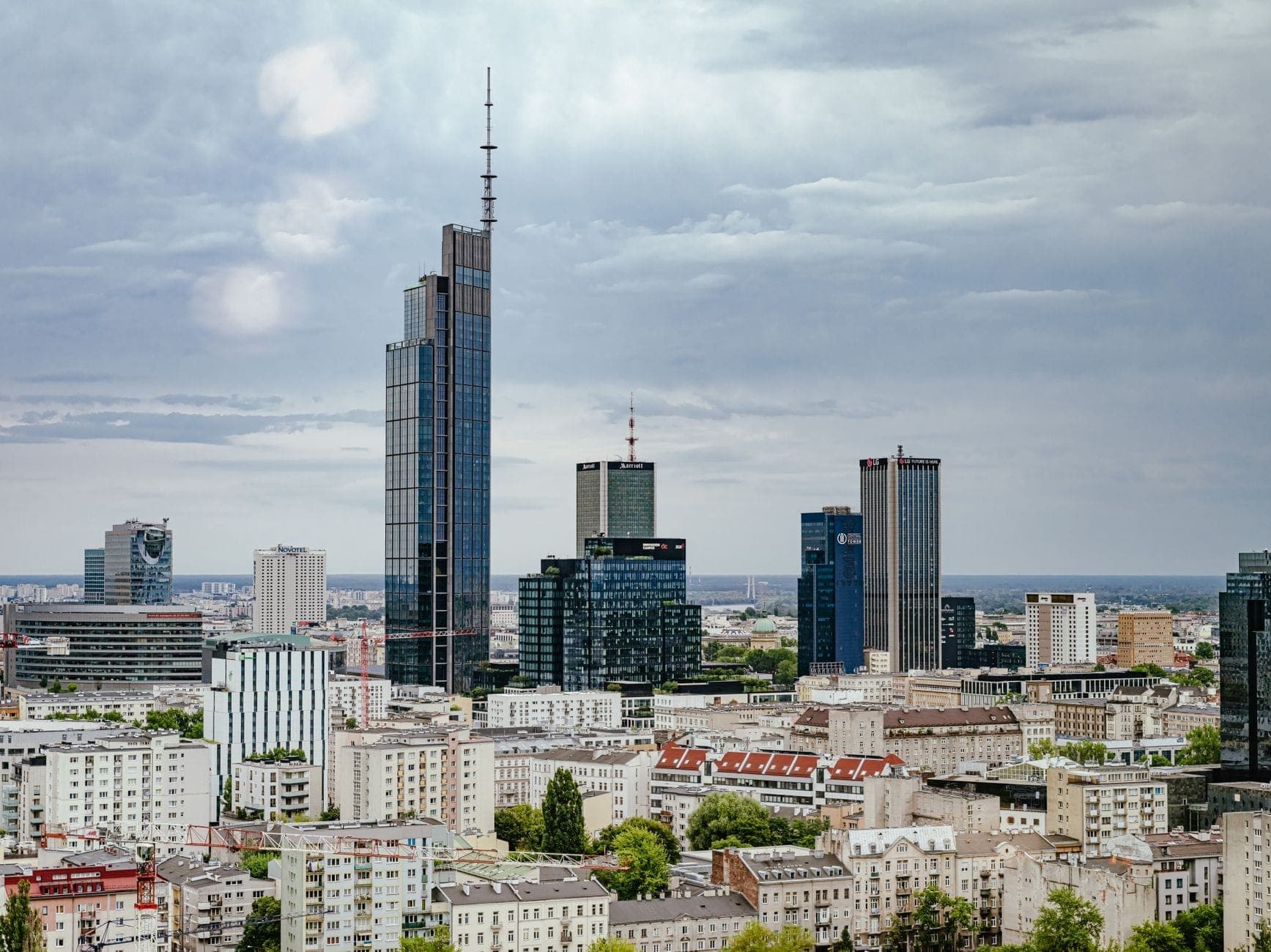 Blick auf die Skyline von Warschau mit dem Varso Tower, der unter einem bewölkten Himmel im Stadtzentrum markant über die umliegenden Gebäude hinausragt.