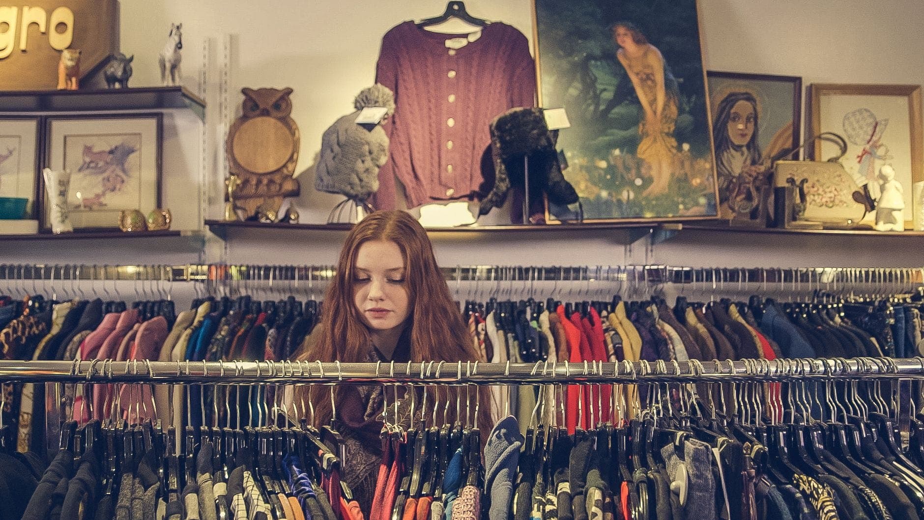 Cô gái trẻ lướt qua dãy áo quần vintage nhiều màu sắc trong một boutique trang trí nghệ thuật và đậm chất retro.