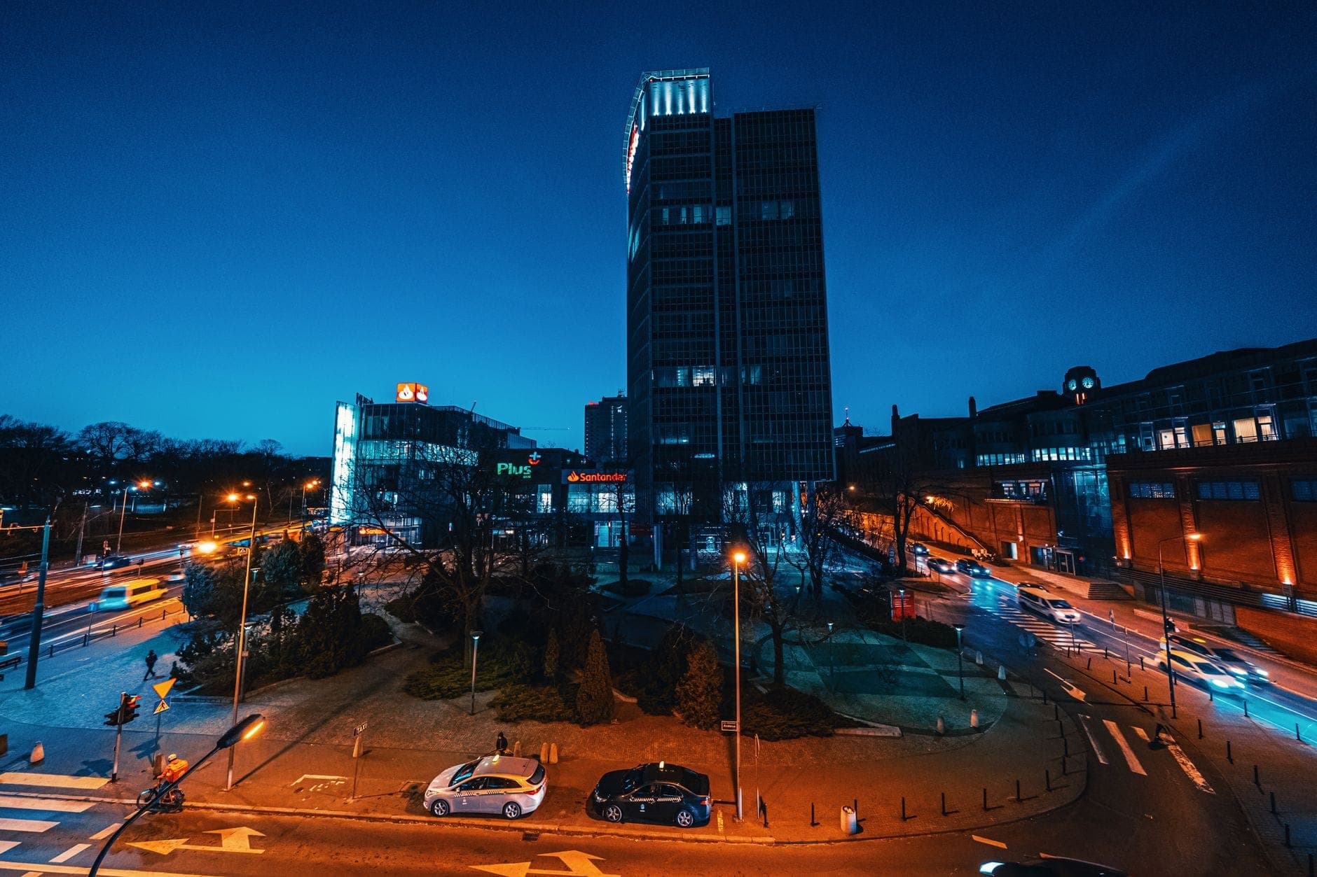 Nächtliche Stadtlandschaft mit einem markanten Turm, Kreisverkehren und beleuchteten Straßen im Stadtteil Praga in Warschau.