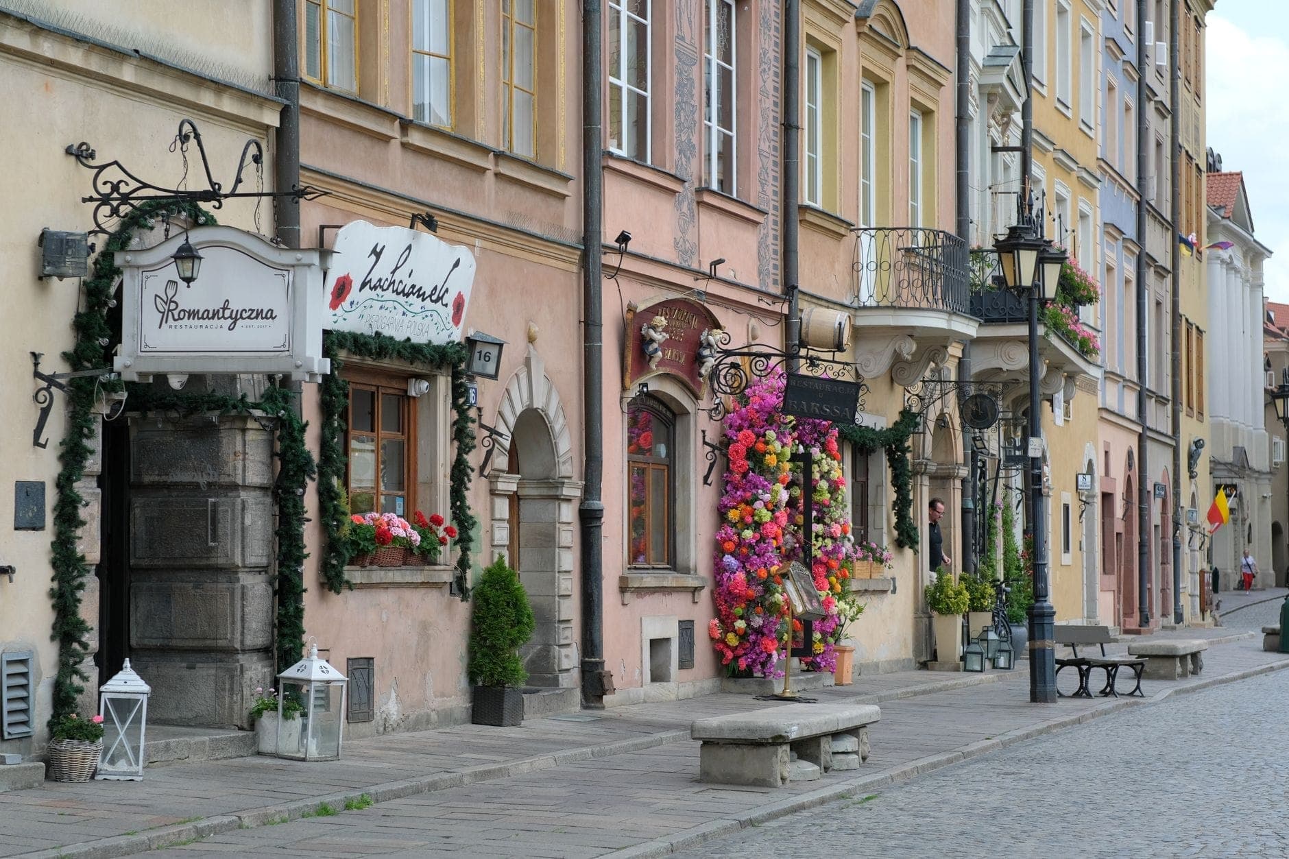Charmante Reihe von Cafés und Restaurants mit Blumendekorationen auf einer Kopfsteinpflasterstraße in der Warschauer Altstadt