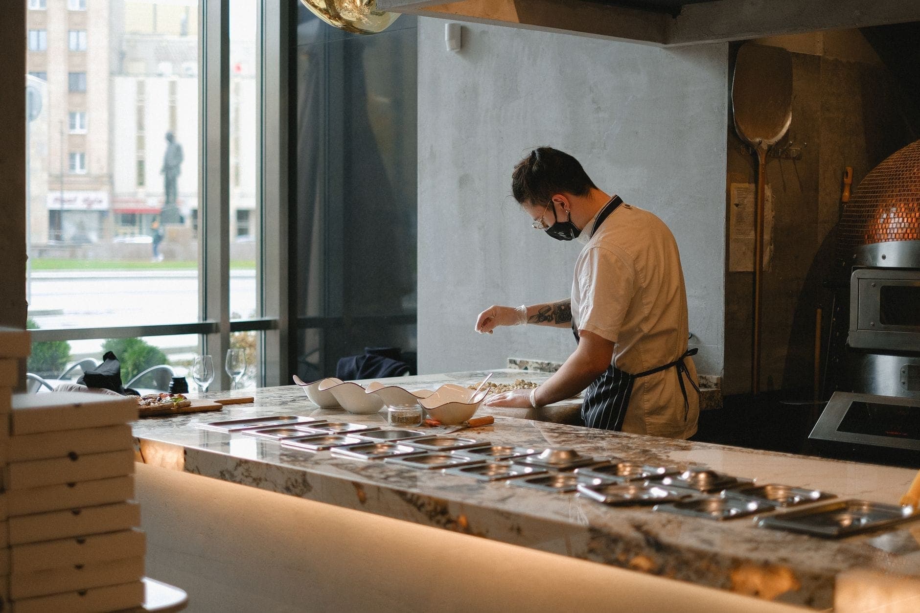 Szef kuchni w nowoczesnej kuchni restauracyjnej przygotowujący jedzenie przy dużym oknie z widokiem na miasto Warszawa