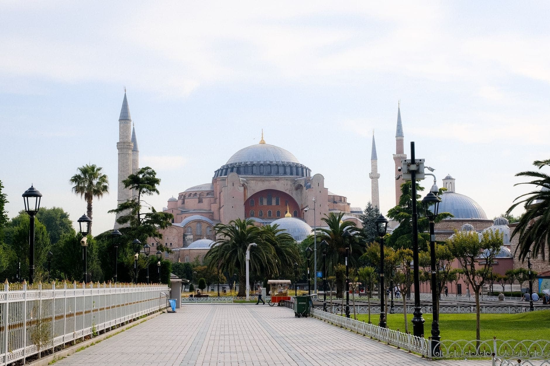 Vista diurna della Hagia Sophia a Sultanahmet, Istanbul, vista da un percorso pedonale fiancheggiato da palme e lampioni.